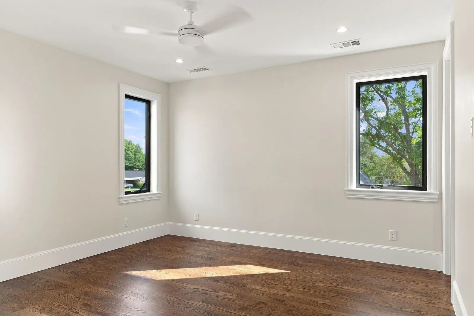 Hardwood flooring, recessed lighting, ceiling fan, and two large windows with white trim