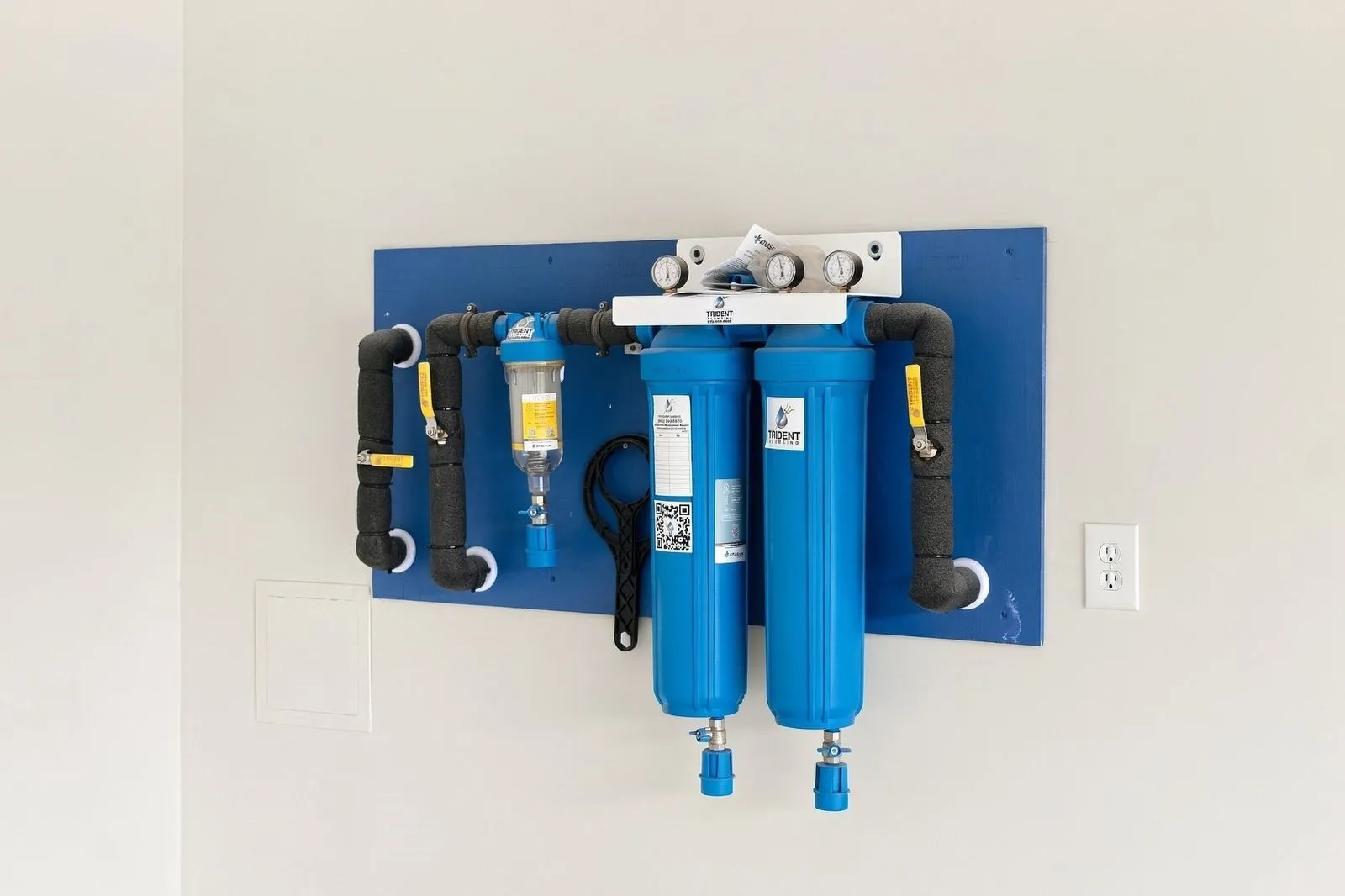 Wall-mounted water filtration system with insulated piping and pressure gauges