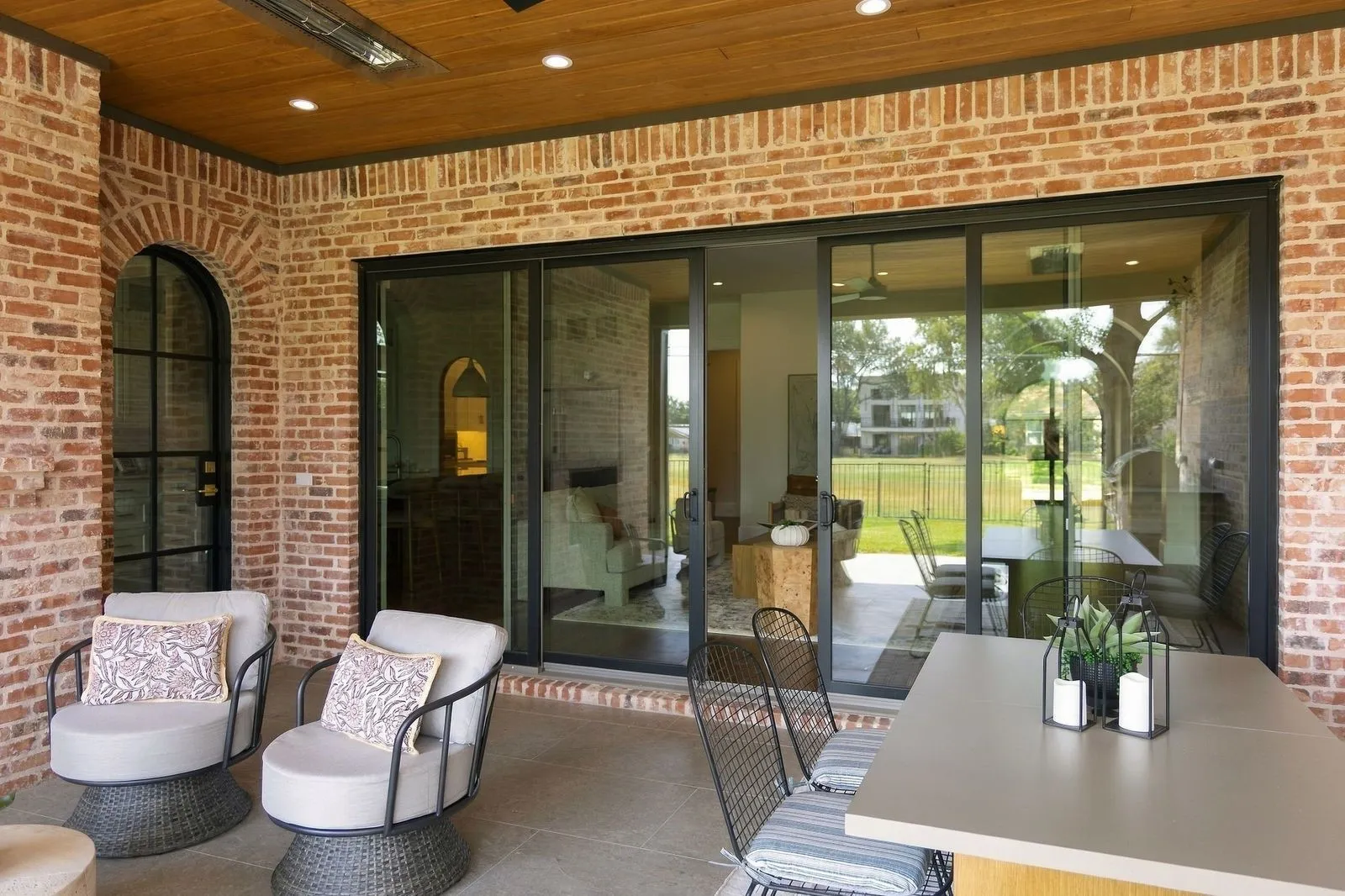 Brick exterior with wood-finish ceiling, recessed lighting, and an arched black-framed door