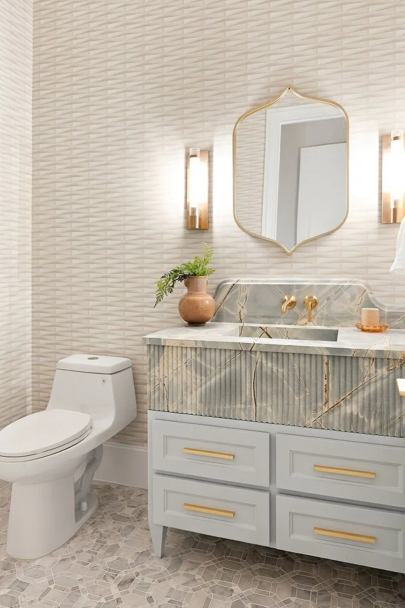 Textured wall tiling, custom vanity with fluted detailing, integrated sink basin, gold-finish hardware, and geometric floor tiling