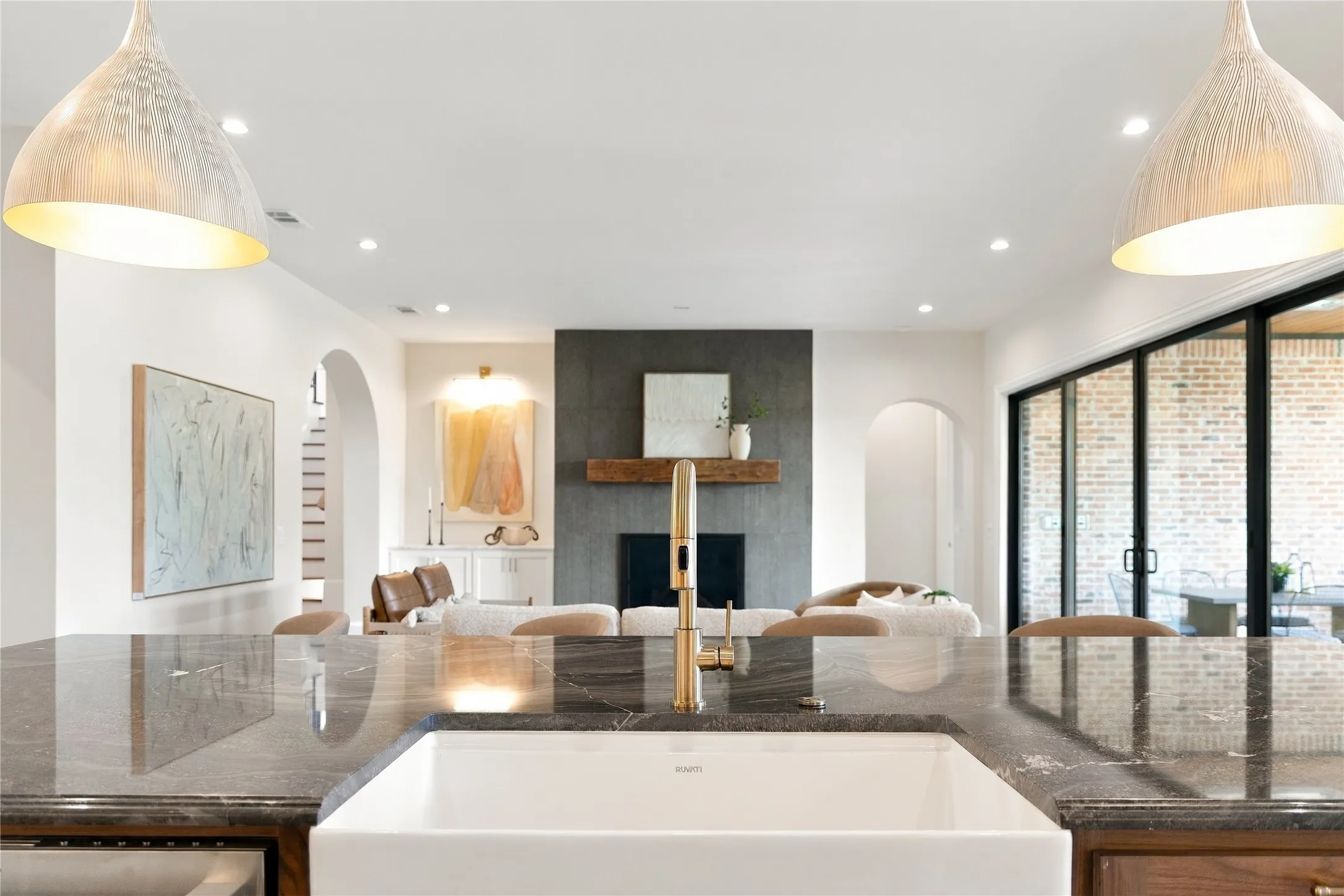 Kitchen island featuring a white apron front sink, brass-finish faucet, and dark stone countertop