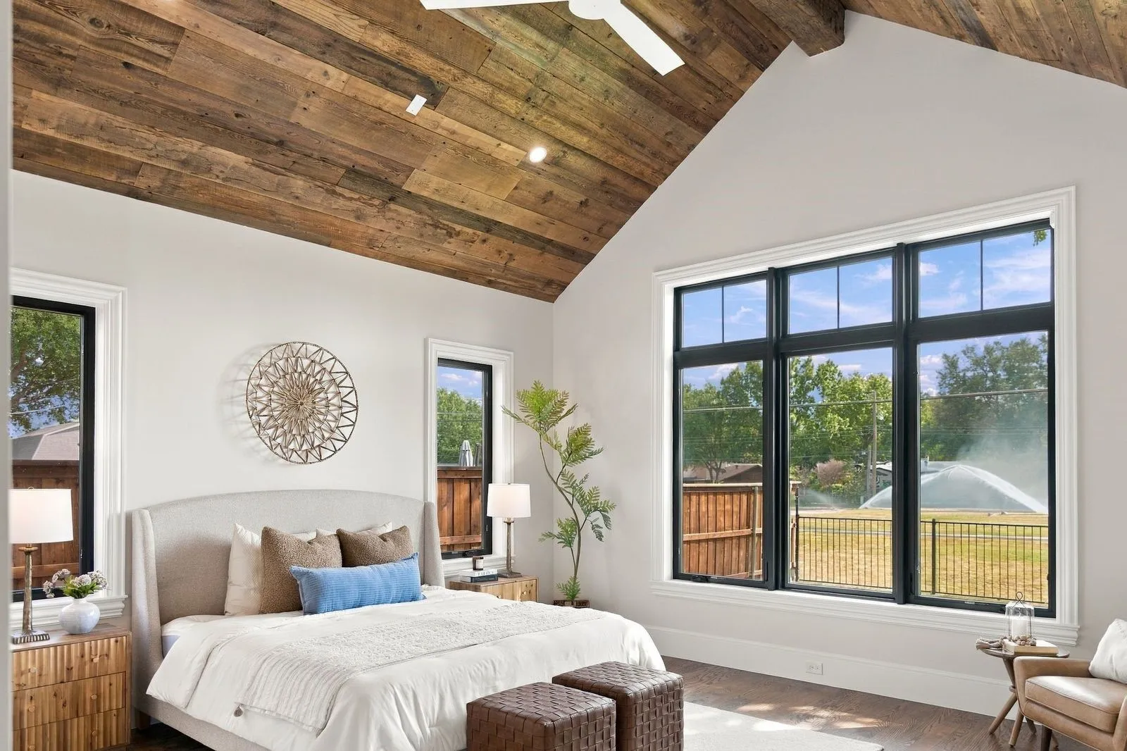 Vaulted wood-plank ceiling with exposed beams, large multi-pane windows, and wood-finish flooring
