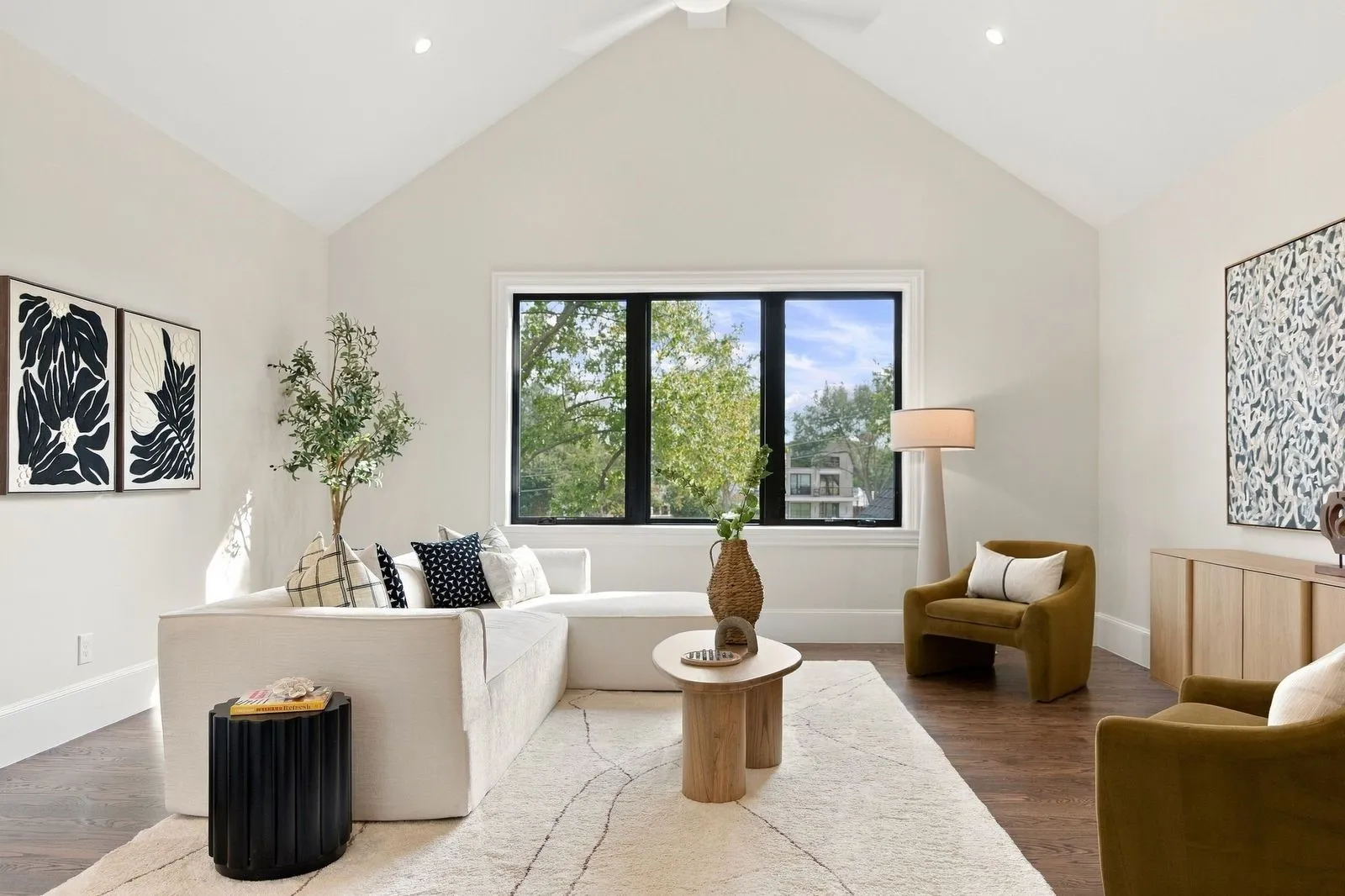 Vaulted ceiling, recessed lighting, wood-finish flooring, large multi-pane window with dark trim, and a ceiling fan