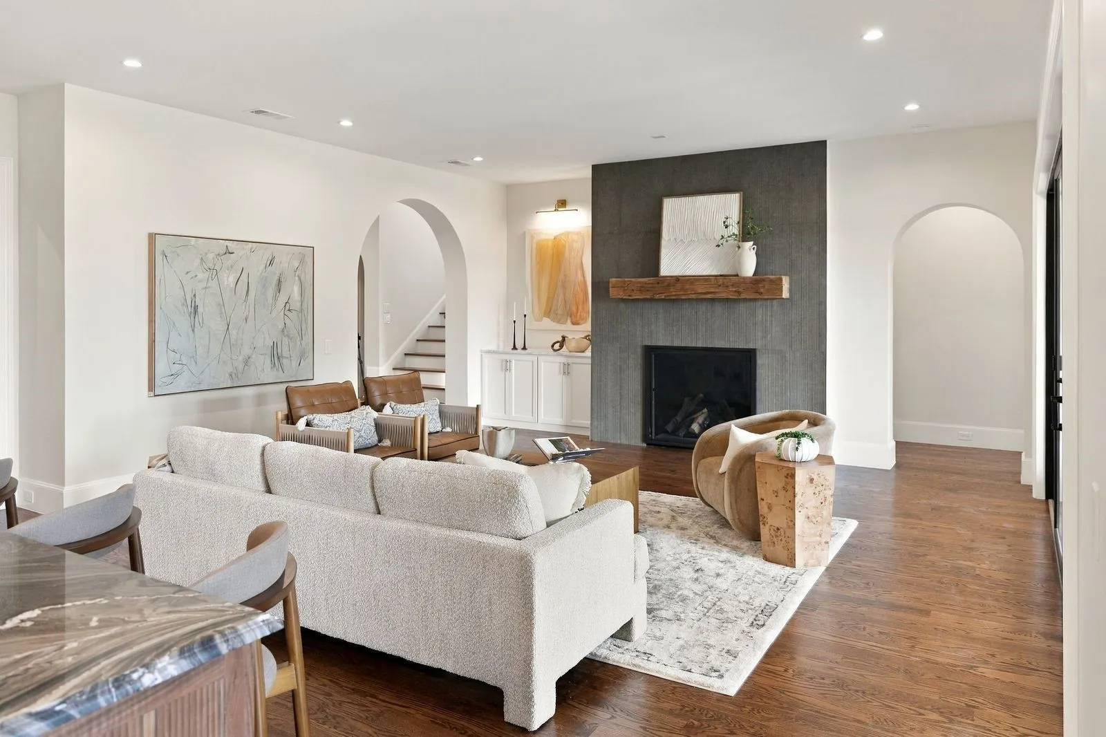 Recessed lighting, wood-finish flooring, arched doorways, a built-in fireplace with a stone surround, and a wood mantel