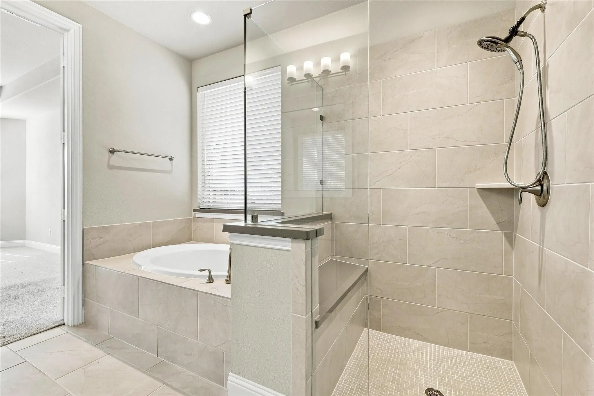 Spacious bathroom featuring a built-in soaking tub, a tiled walk-in shower with bench seating, and a dual-head shower system