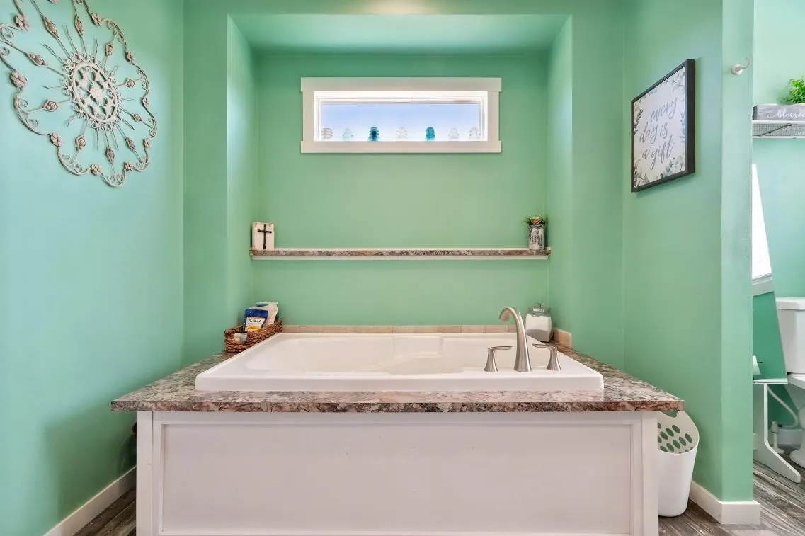 Built-in soaking tub with deck-mounted faucet, surrounded by a stone-look countertop