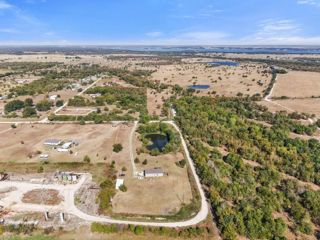 Expansive rural acreage featuring a natural pond, scattered trees, and dirt road​​‌​​​​‌​​‌‌​‌‌​​​‌‌​‌​‌​‌​​​‌​​ access