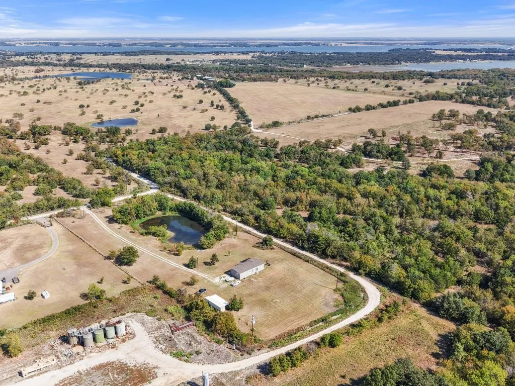 Expansive rural property featuring a primary residence, multiple outbuildings, and a private pond