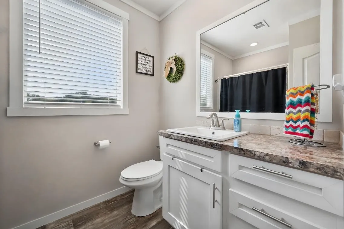 Bathroom featuring a white vanity with slab-front cabinetry, a rectangular undermount sink, and a framed mirror