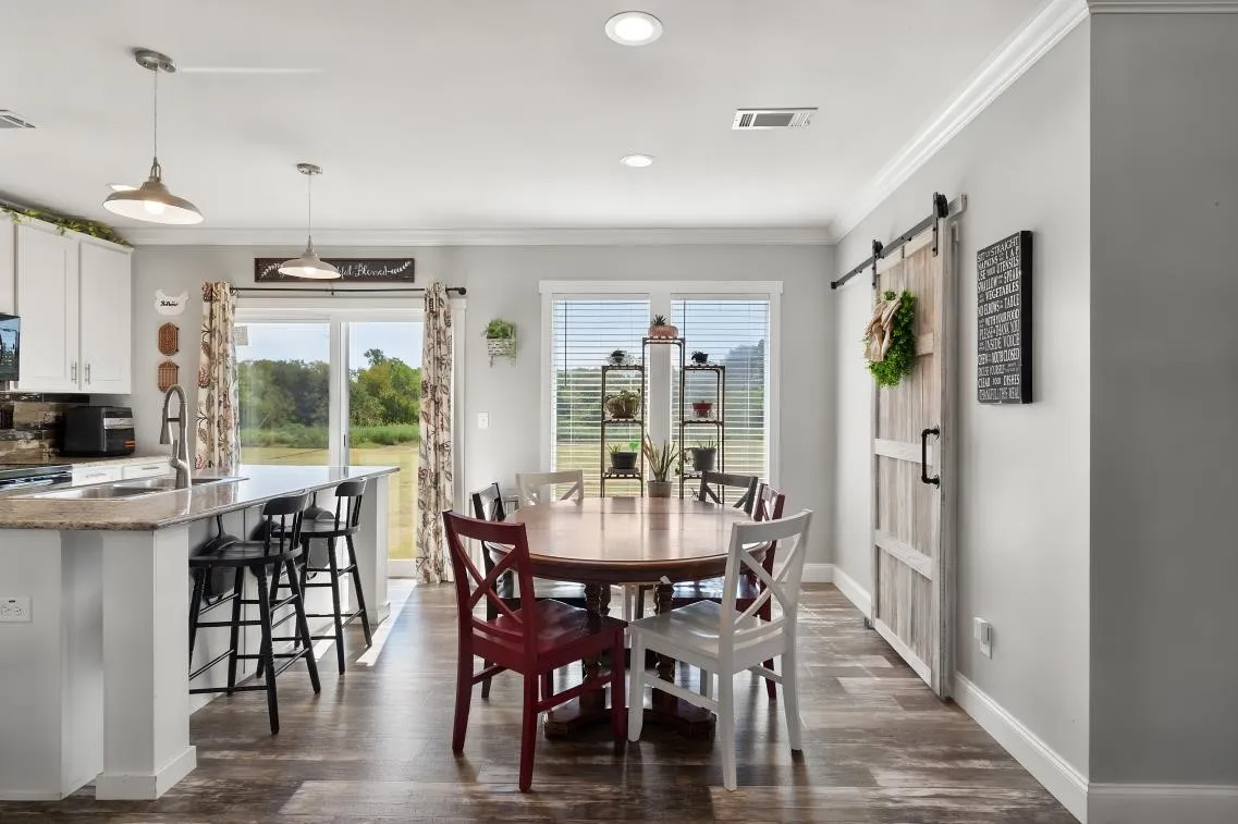 Kitchen island with granite countertop, white shaker-style cabinetry, wood-finish flooring, and sliding glass doors