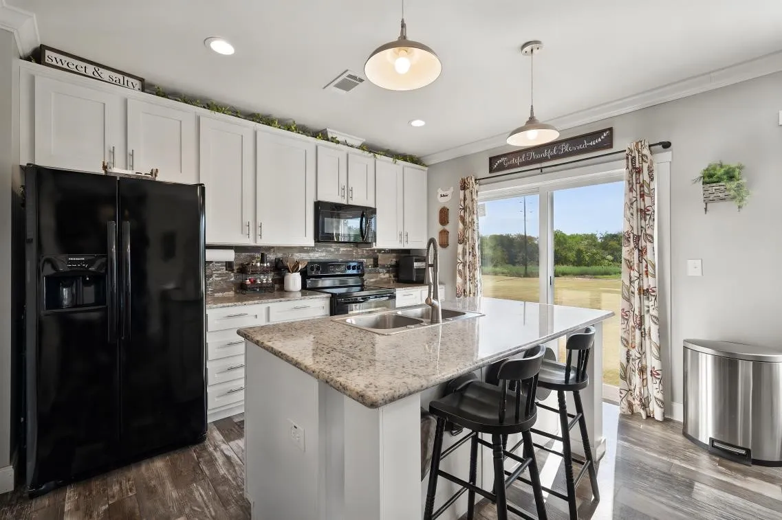 Kitchen featuring white cabinetry, wood-finish flooring, a central island with countertop seating, and sliding glass doors
