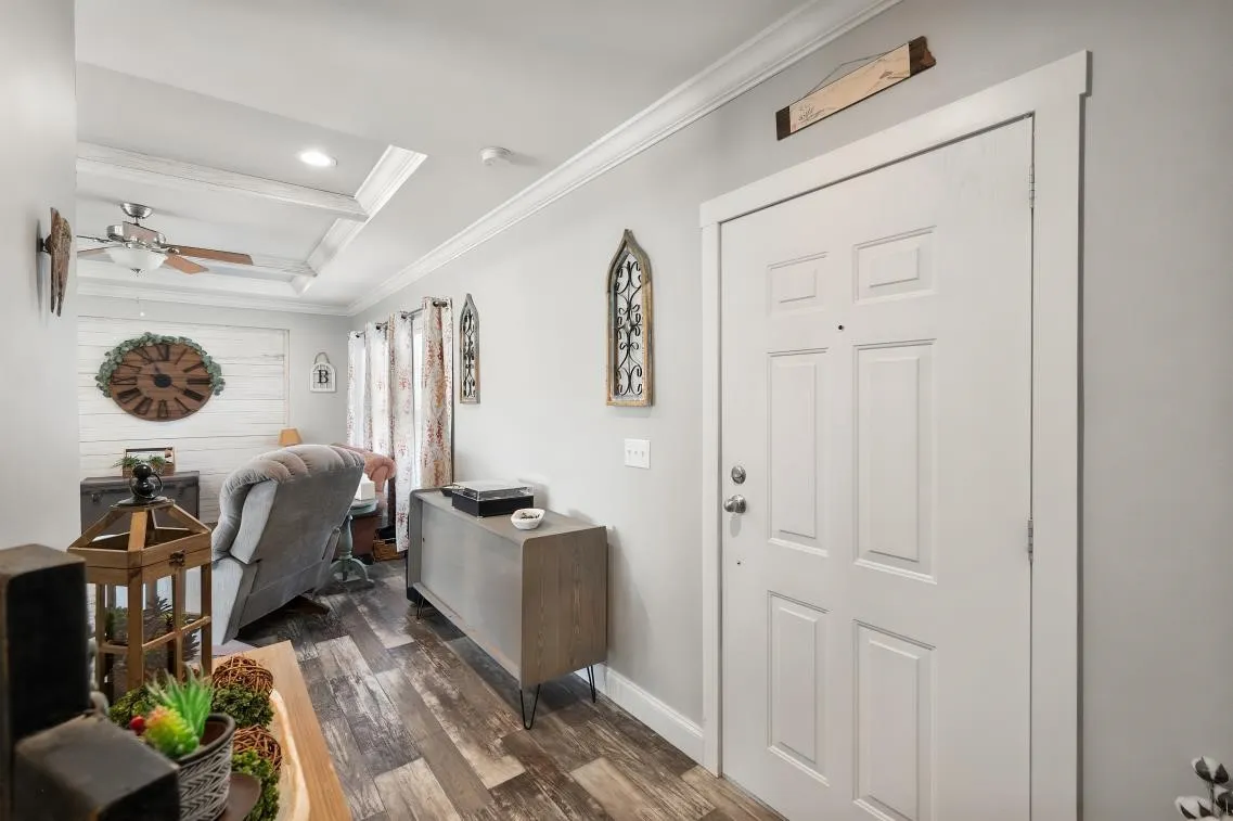 Entrance hall with wood-finish flooring, white paneled door, and crown molding