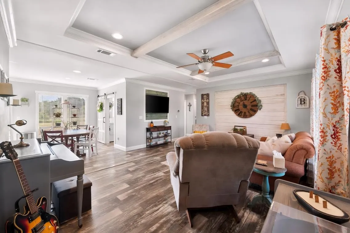 Tray ceiling with exposed wood beams, recessed lighting, wood-finish flooring, and a ceiling fan
