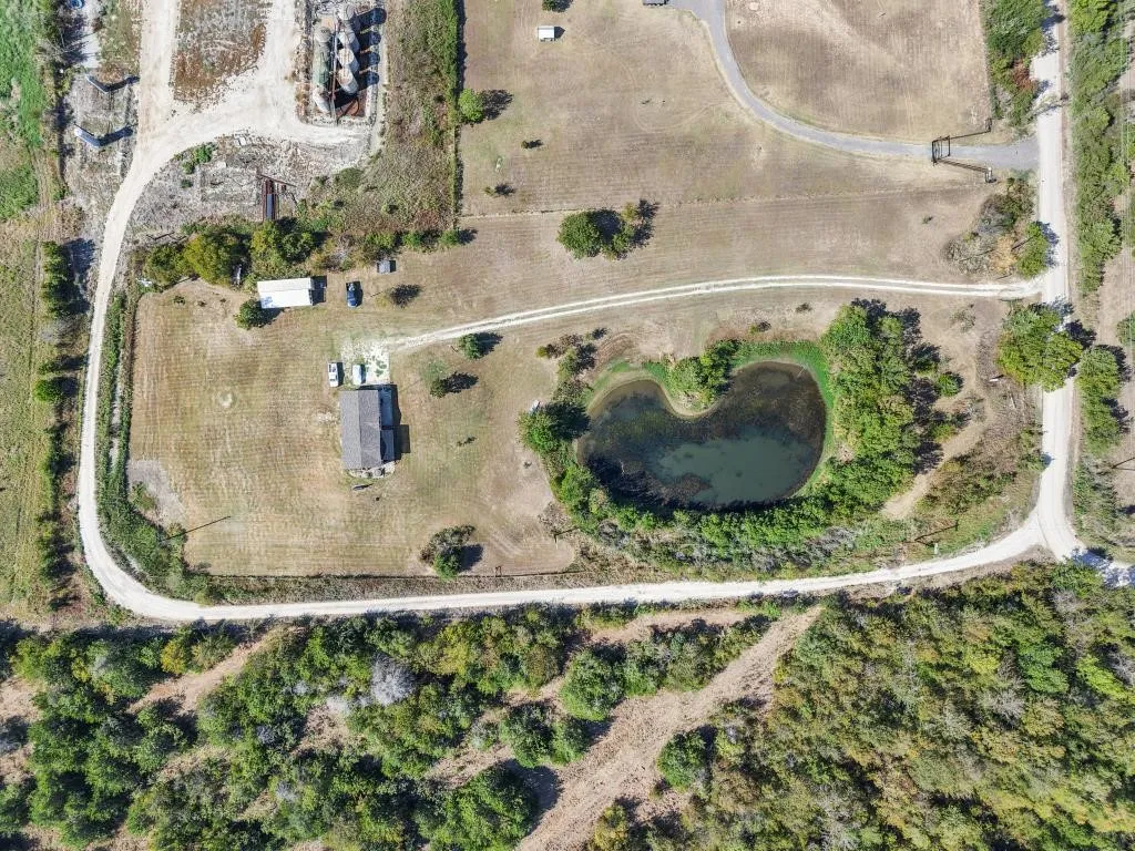 Expansive rural property featuring a private pond, natural landscaping, and established roadways