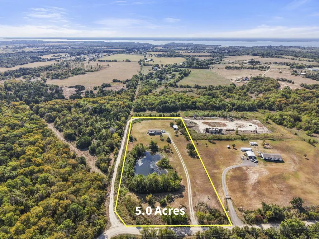 Expansive 5.0-acre property featuring a private pond, mature trees, and a dirt road entrance