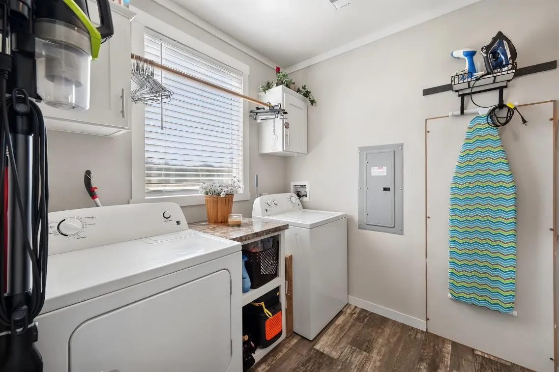 Wood-finish flooring, white cabinetry, integrated countertop space, and window with blinds