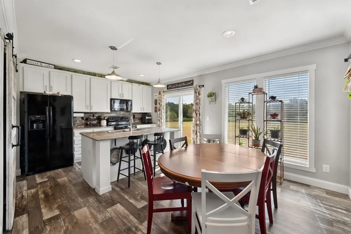 Kitchen featuring wood-finish flooring, white cabinetry, a kitchen island with seating, a sliding glass door, and recessed lighting