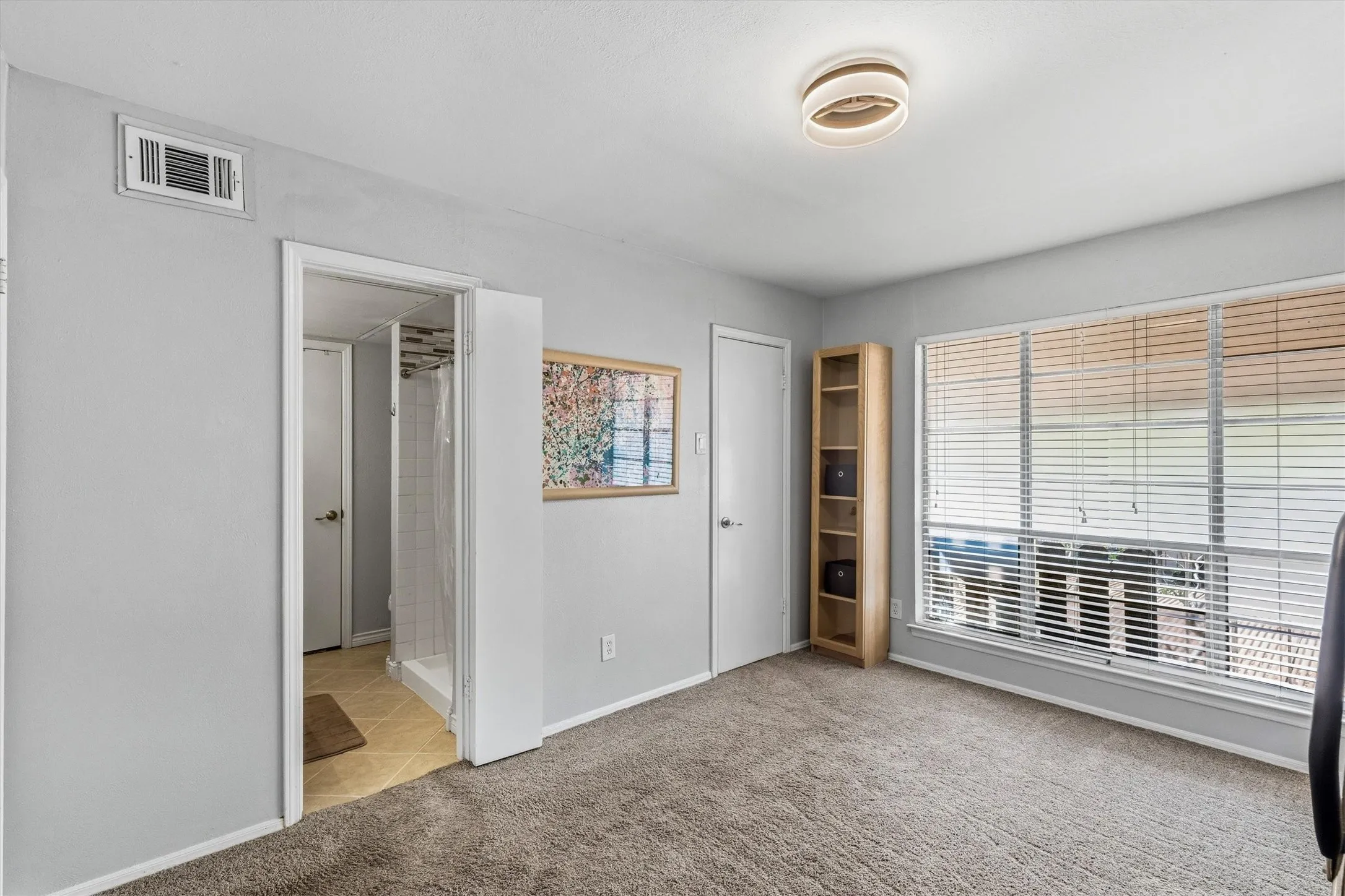 Wall-to-wall carpeting, large window with blinds, and contemporary ceiling light fixture