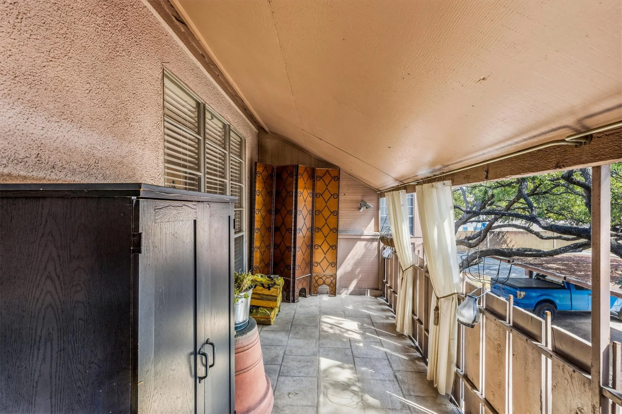 Covered outdoor balcony featuring a tiled floor and a textured exterior wall