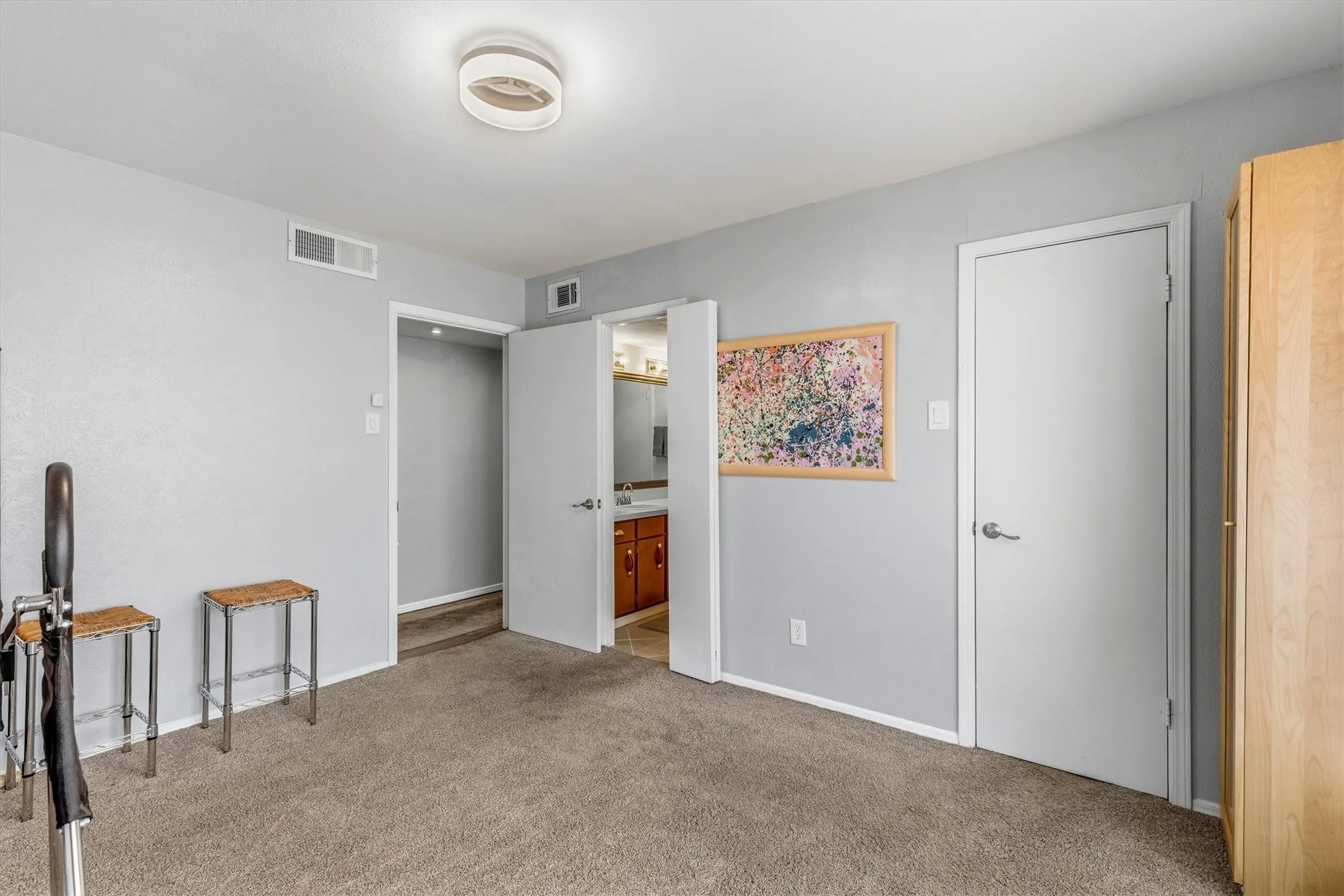 Carpeted flooring with light gray walls, featuring a modern ceiling light fixture