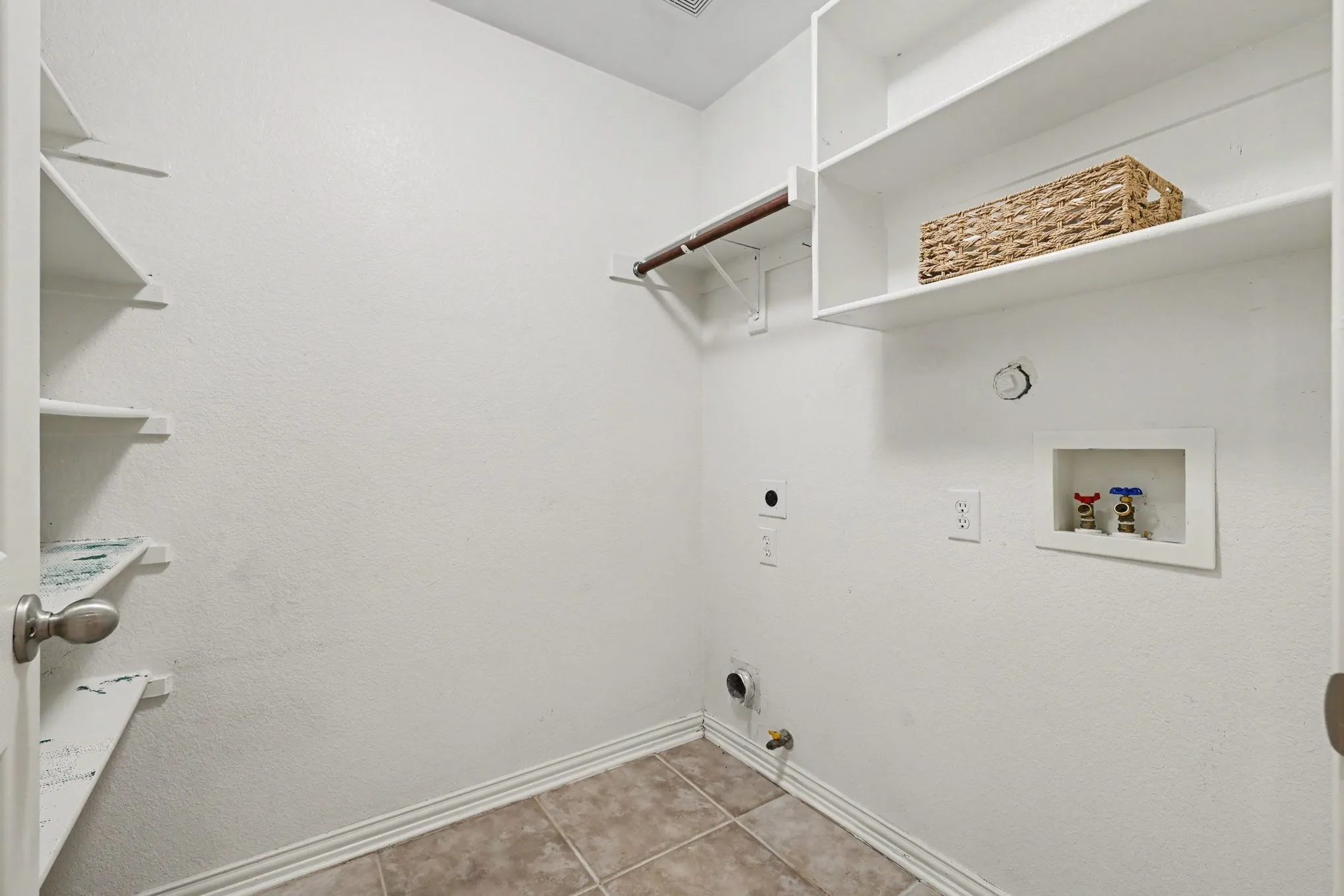 Utility area featuring tile flooring, built-in shelving, and a garment rod