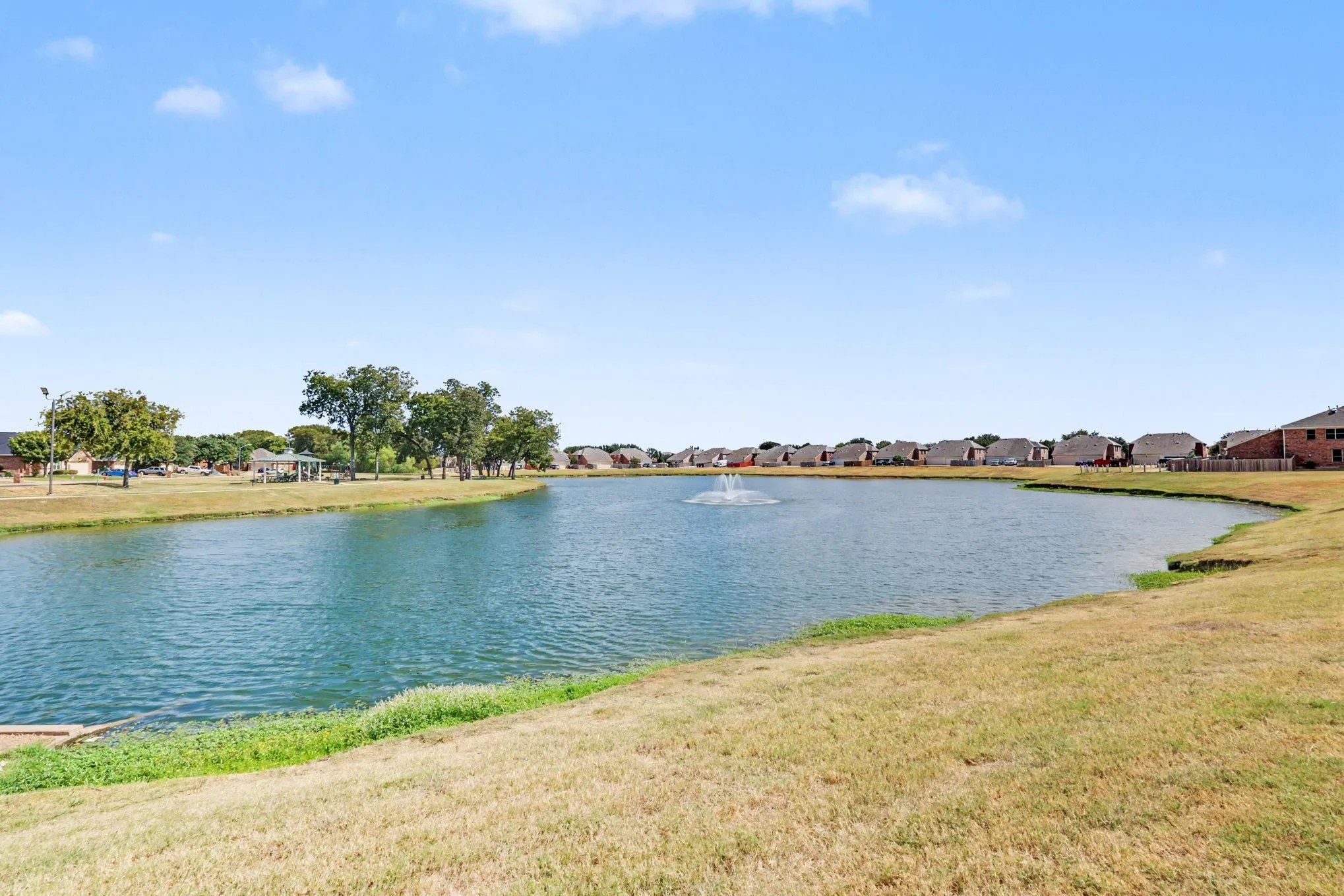Expansive lake with a central fountain, surrounded by green space