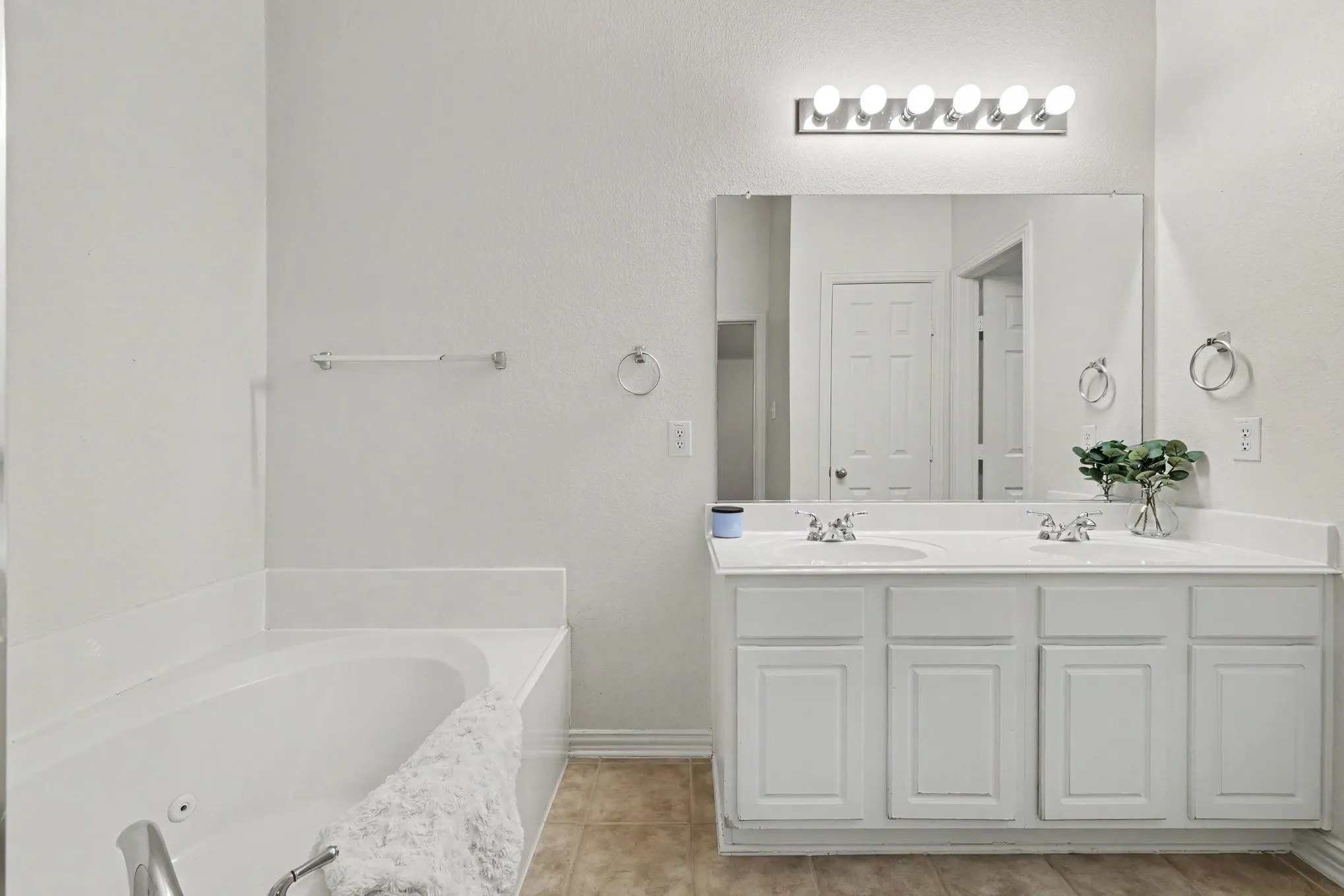 Dual vanity with white cabinetry, rectangular mirror, and bright overhead lighting