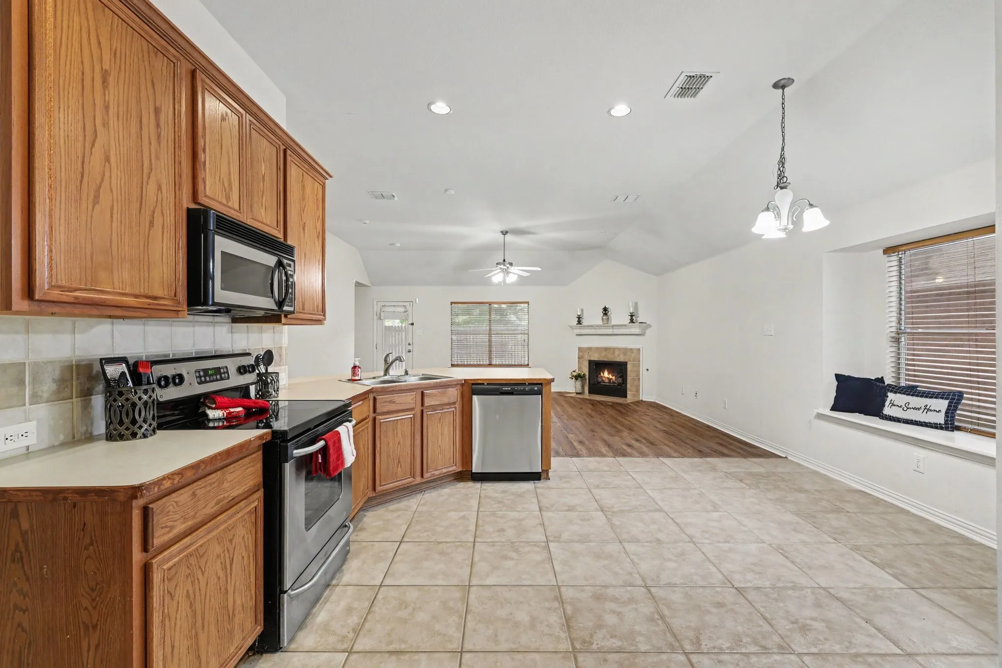 Kitchen with wood cabinetry, stainless steel appliances, and tile flooring