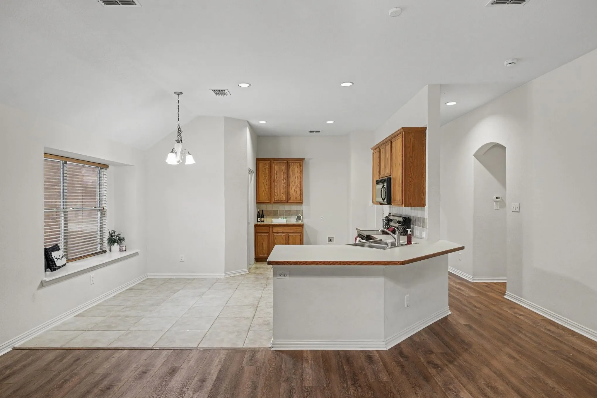 Open concept living space featuring wood-finish flooring, tile flooring, built-in kitchen cabinetry, built-in microwave, and recessed lighting