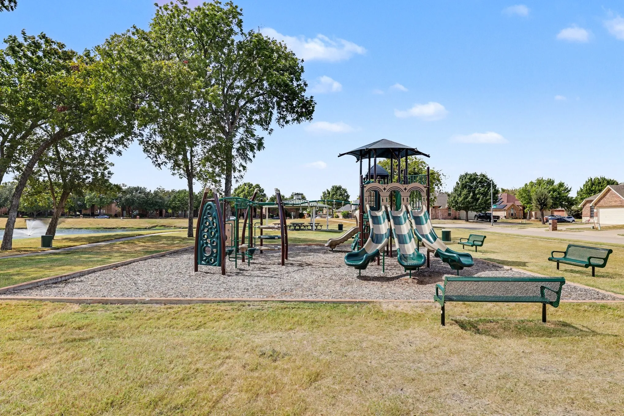 Community playground featuring a multi-level play structure with slides, swings, and climbing elements