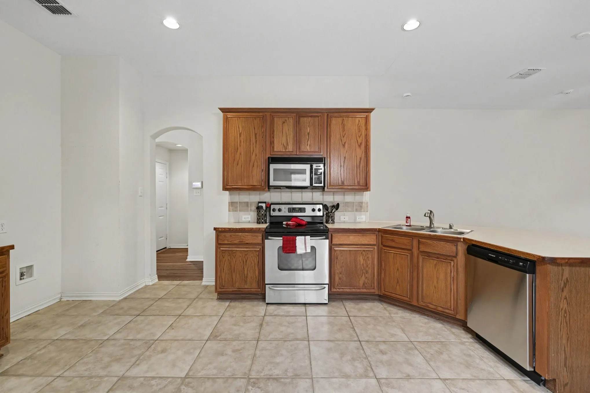 Kitchen featuring wood cabinetry, stainless steel appliances, tile flooring, and a tile backsplash