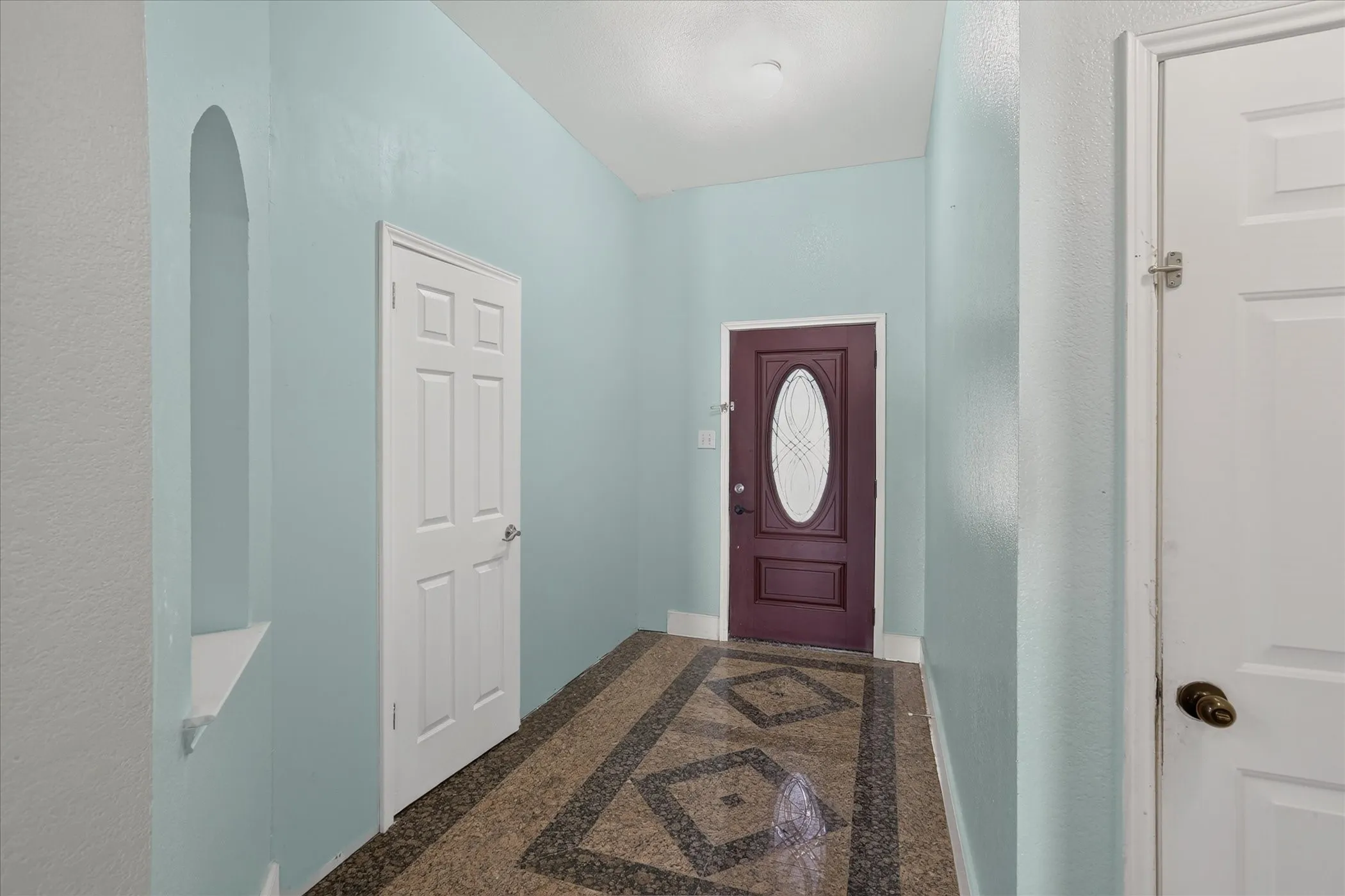 Recessed arched niche, patterned tile flooring, and a six-panel interior door