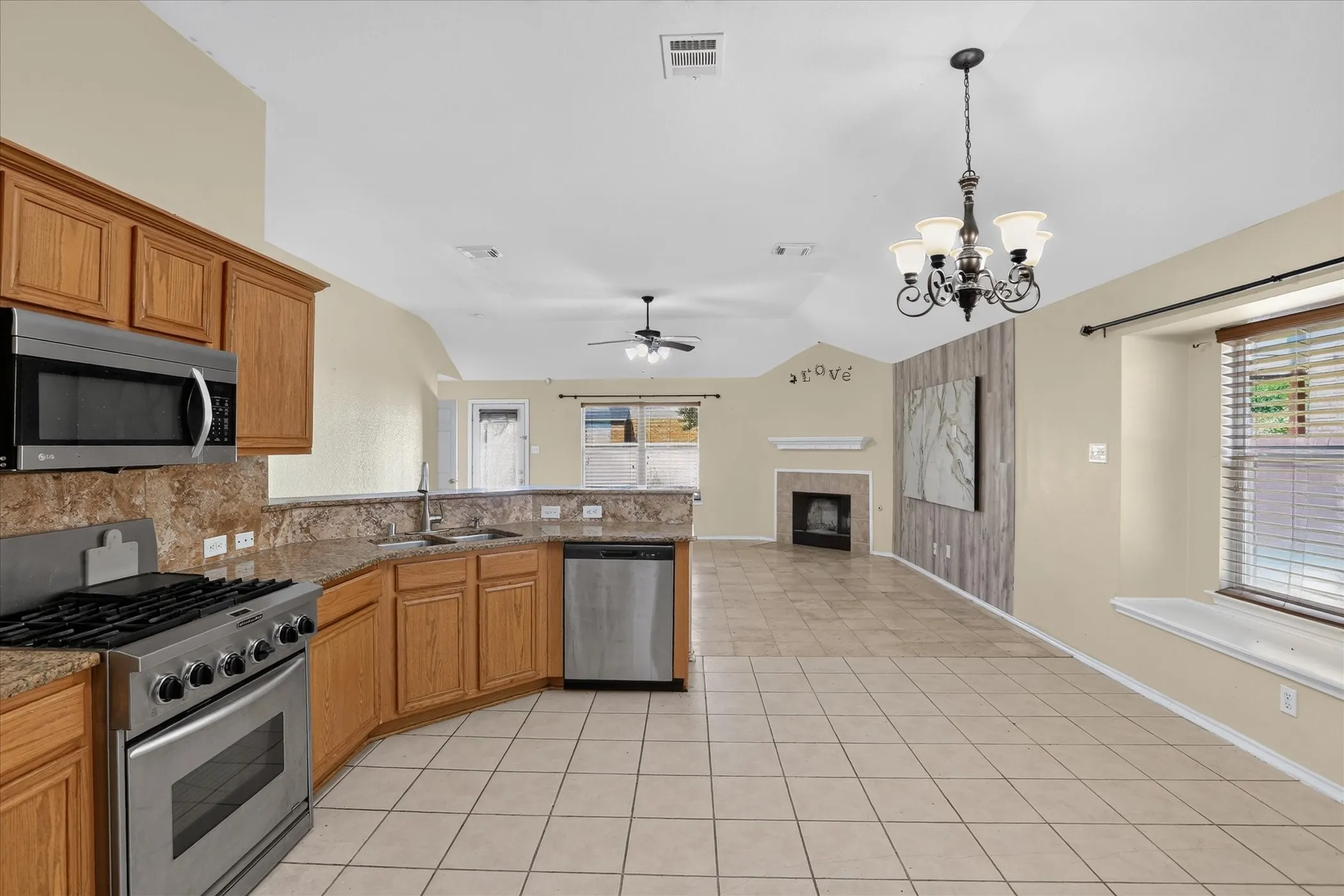 Kitchen featuring wood cabinetry, stainless steel appliances, and a stone-finish countertop with a matching backsplash