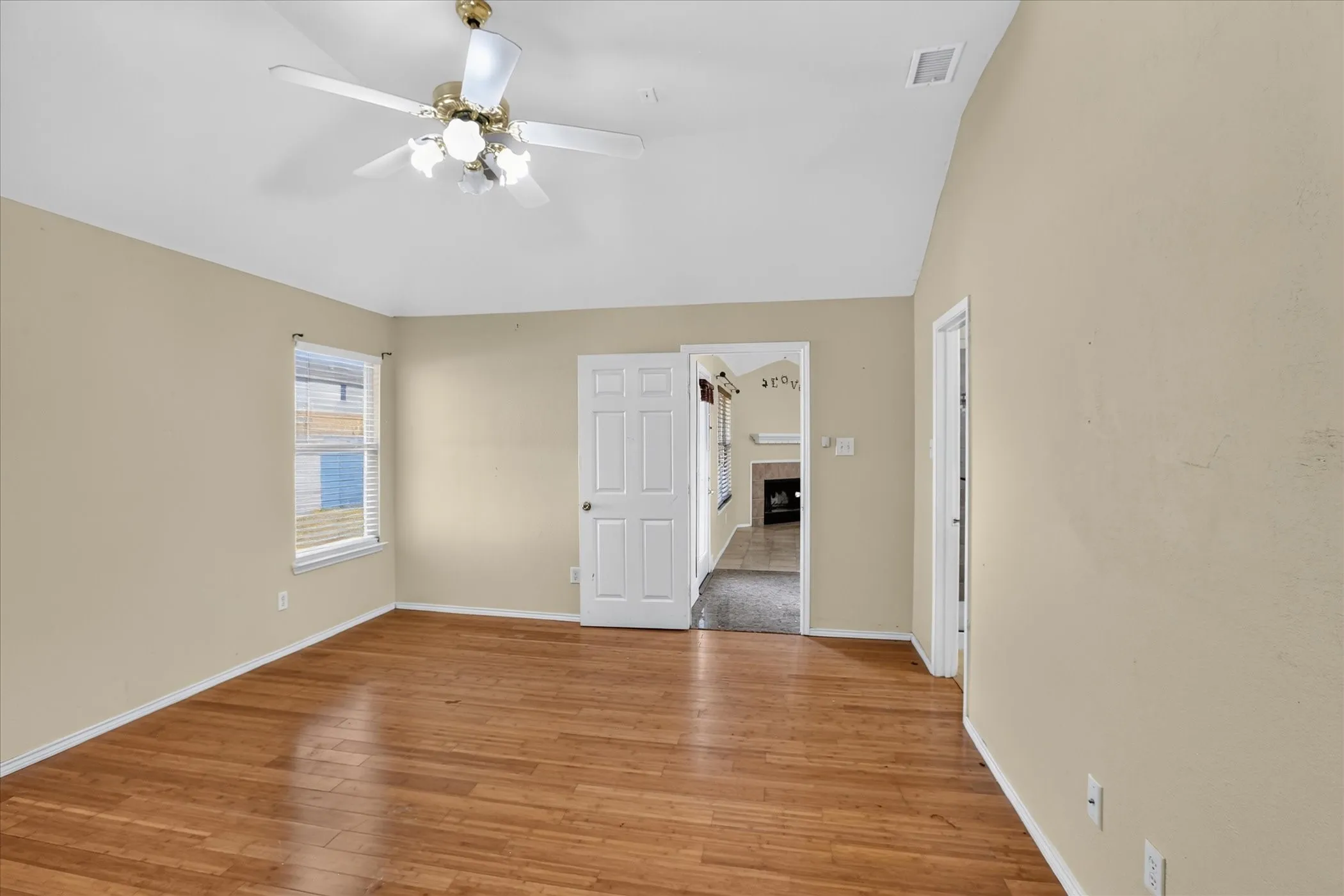 Vaulted ceiling with a ceiling fan, wood-finish flooring, and a paneled door