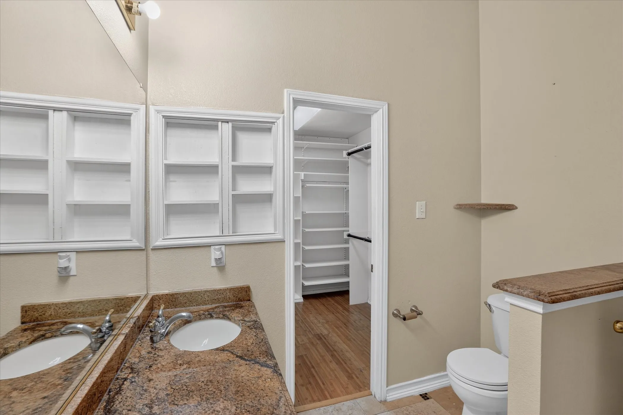 Dual medicine cabinets, a vanity with a stone-finish countertop, and a built-in toilet