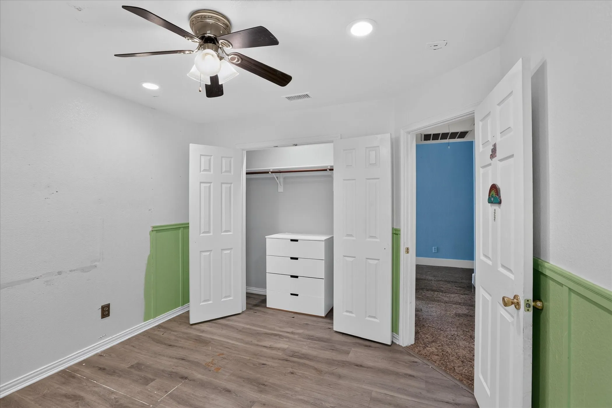 Wood-finish flooring, ceiling fan with integrated lighting, recessed lighting, and a closet with bifold doors