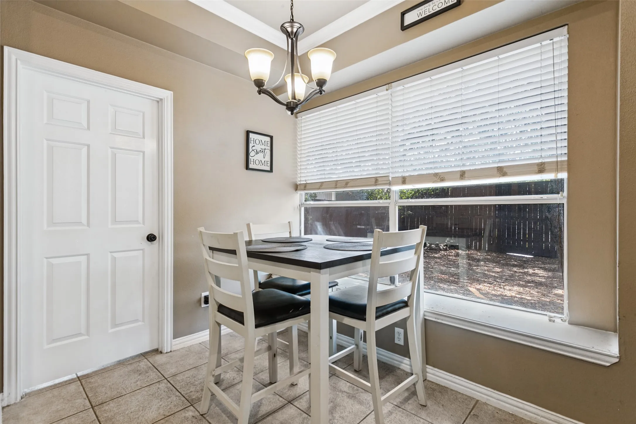 Recessed ceiling with an attached chandelier, a large window, and tile flooring