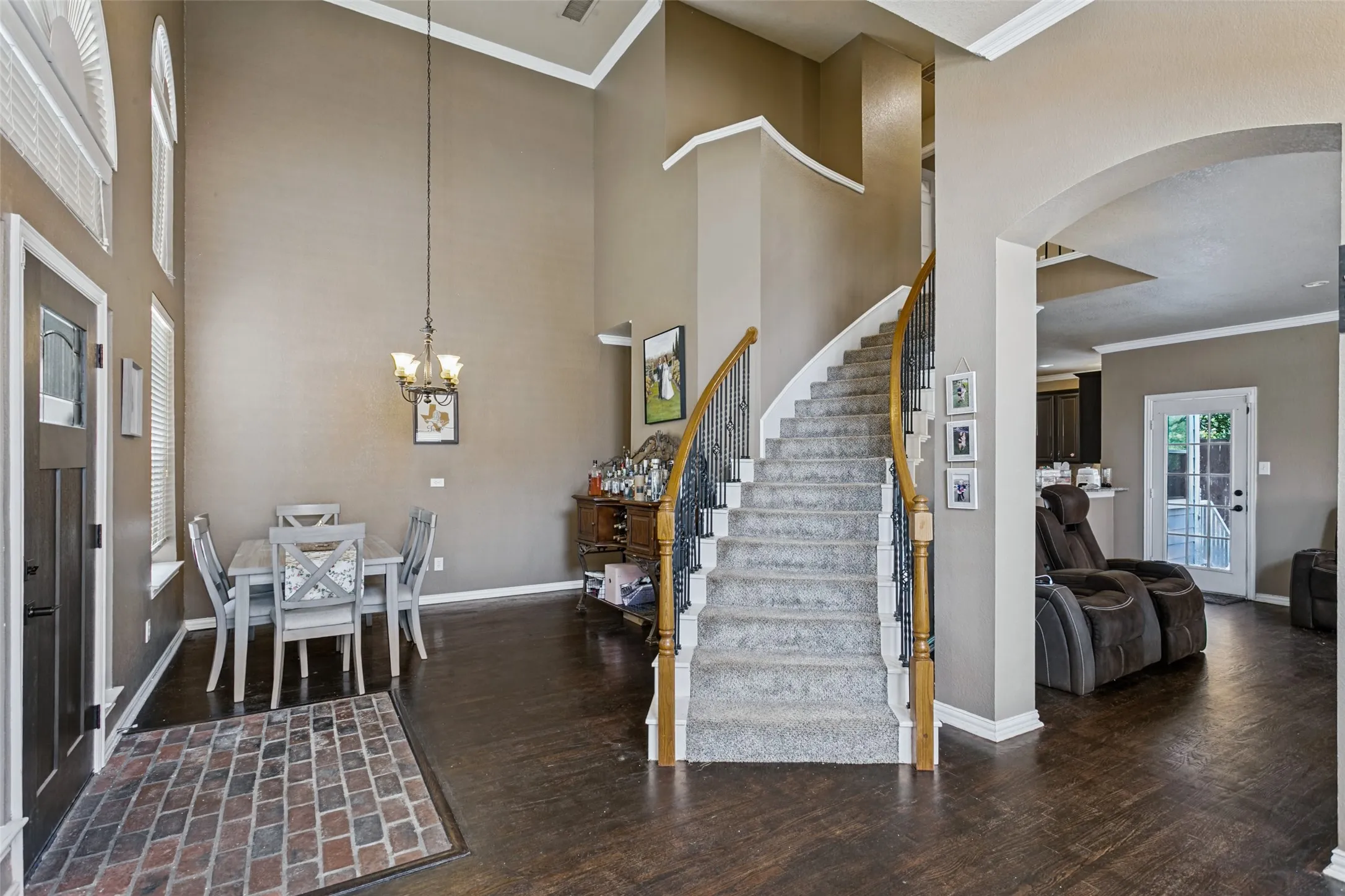 Two-story foyer with a grand curved staircase featuring wrought iron balusters and a wood handrail