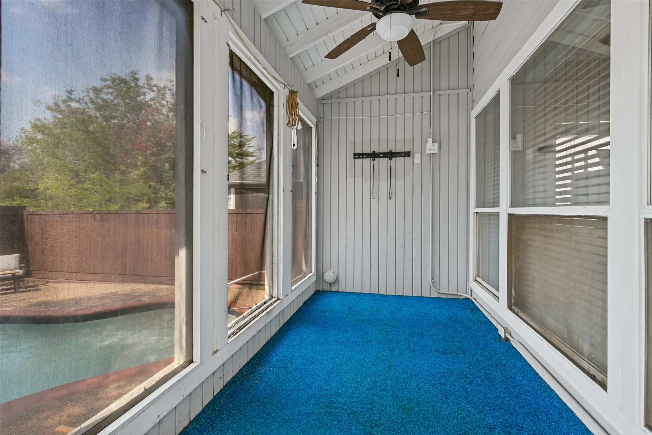 Enclosed patio with slatted walls, a vaulted ceiling, and a ceiling fan
