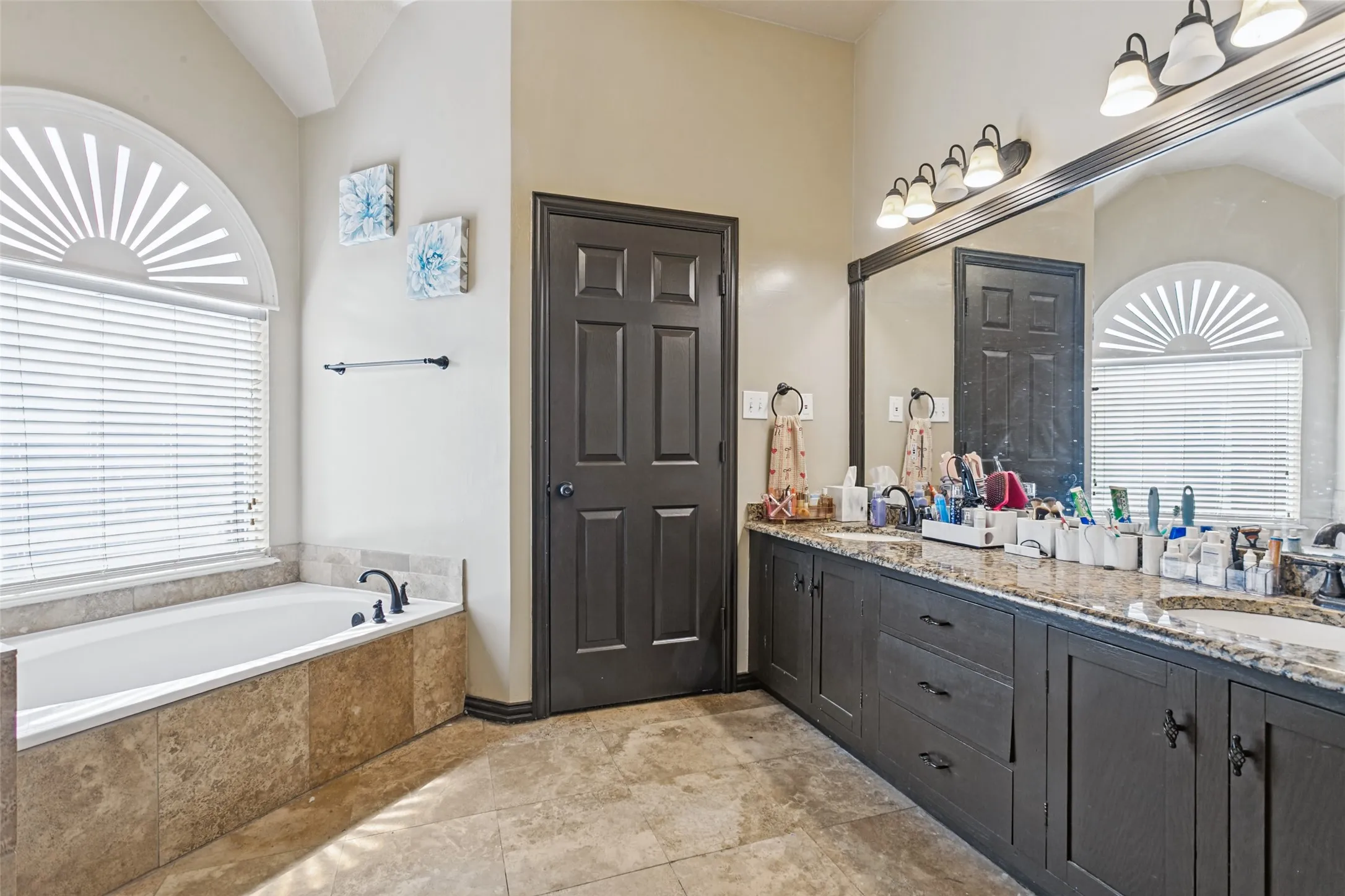 Dual vanity with granite-style countertops, integrated sinks, and dark wood-finish cabinetry