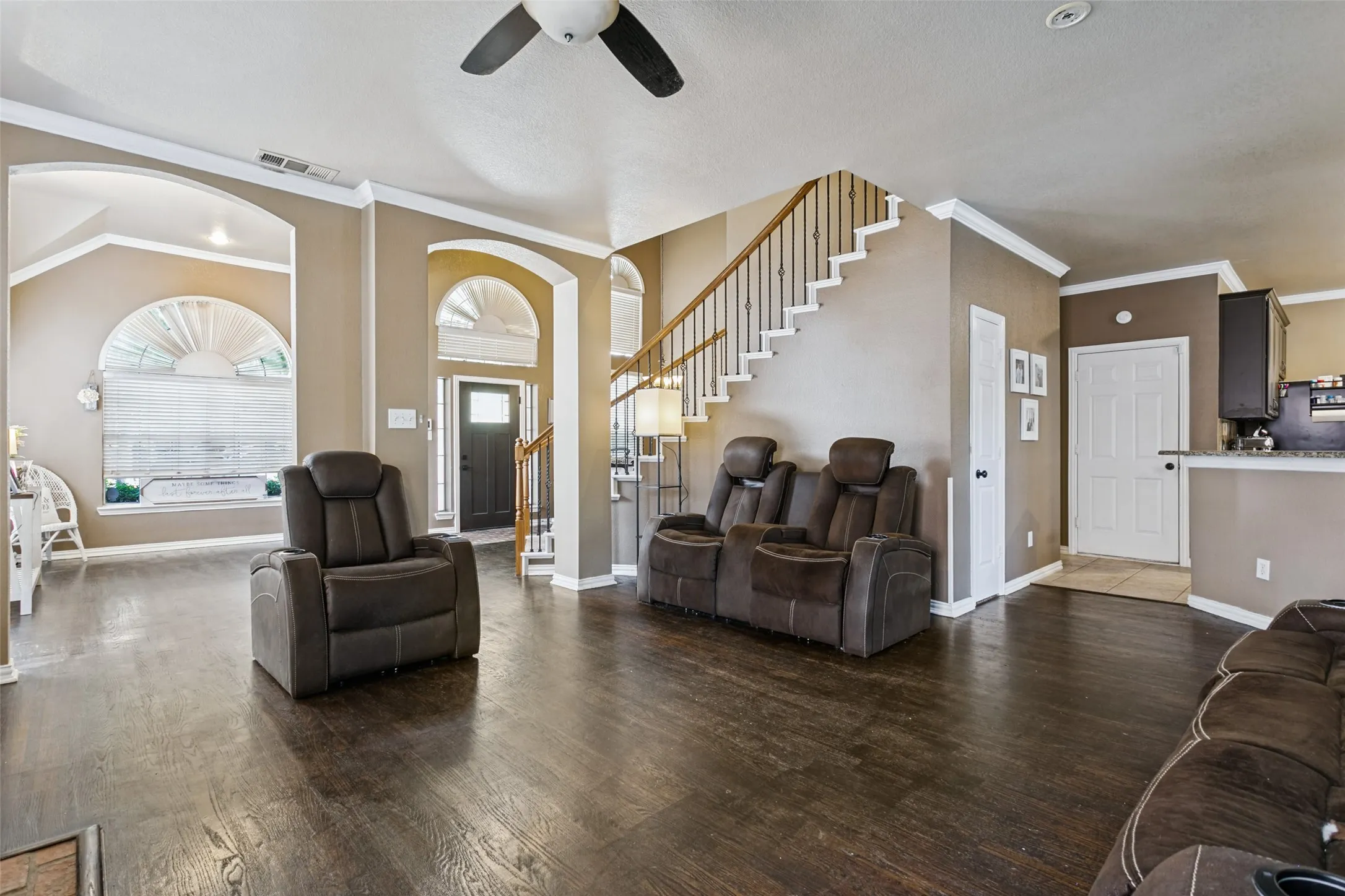 Open-concept living area featuring dark wood-finish flooring throughout, recessed ceiling lighting, and a ceiling fan