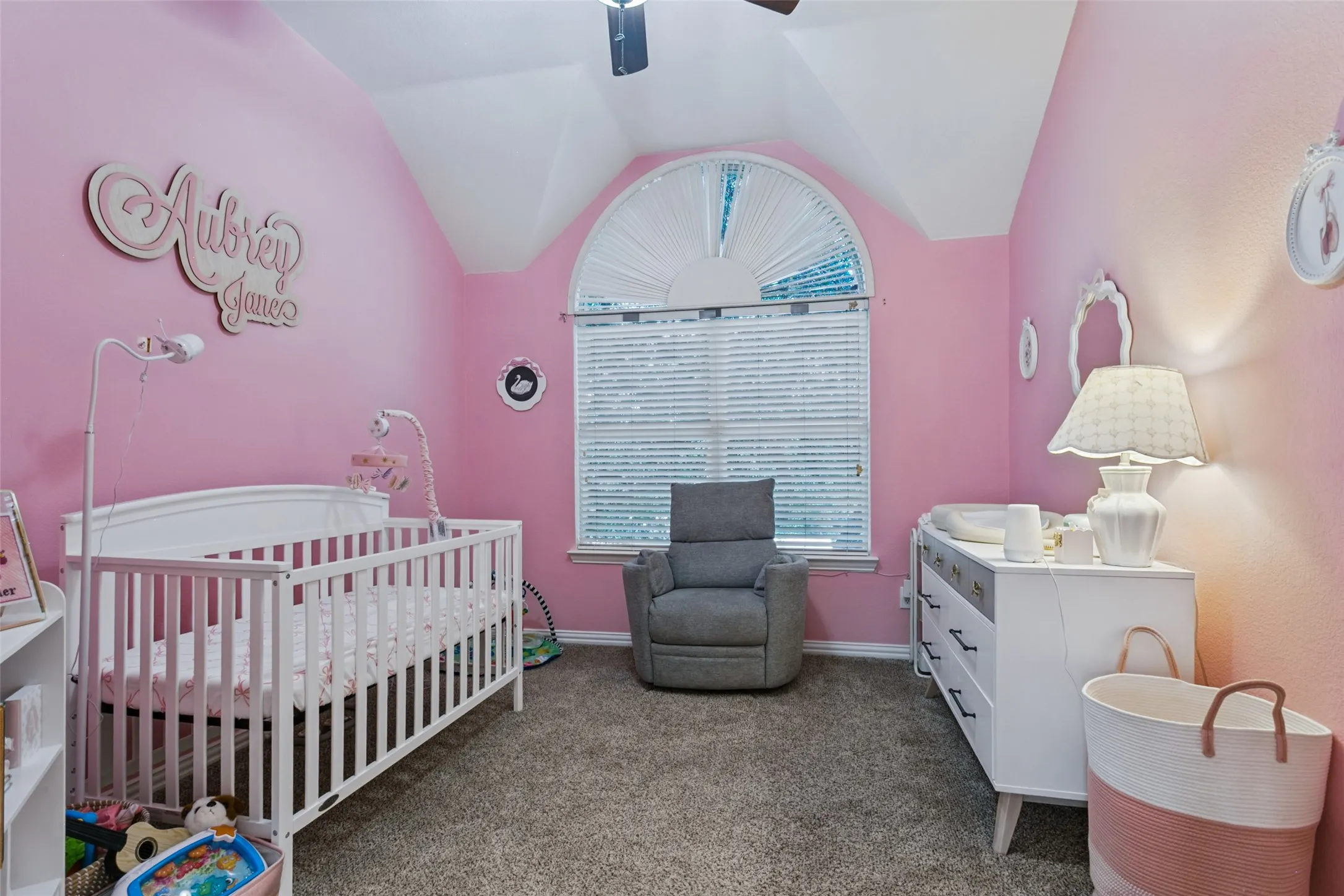 Tray ceiling with an arched window, textured wall finish, and neutral carpet flooring