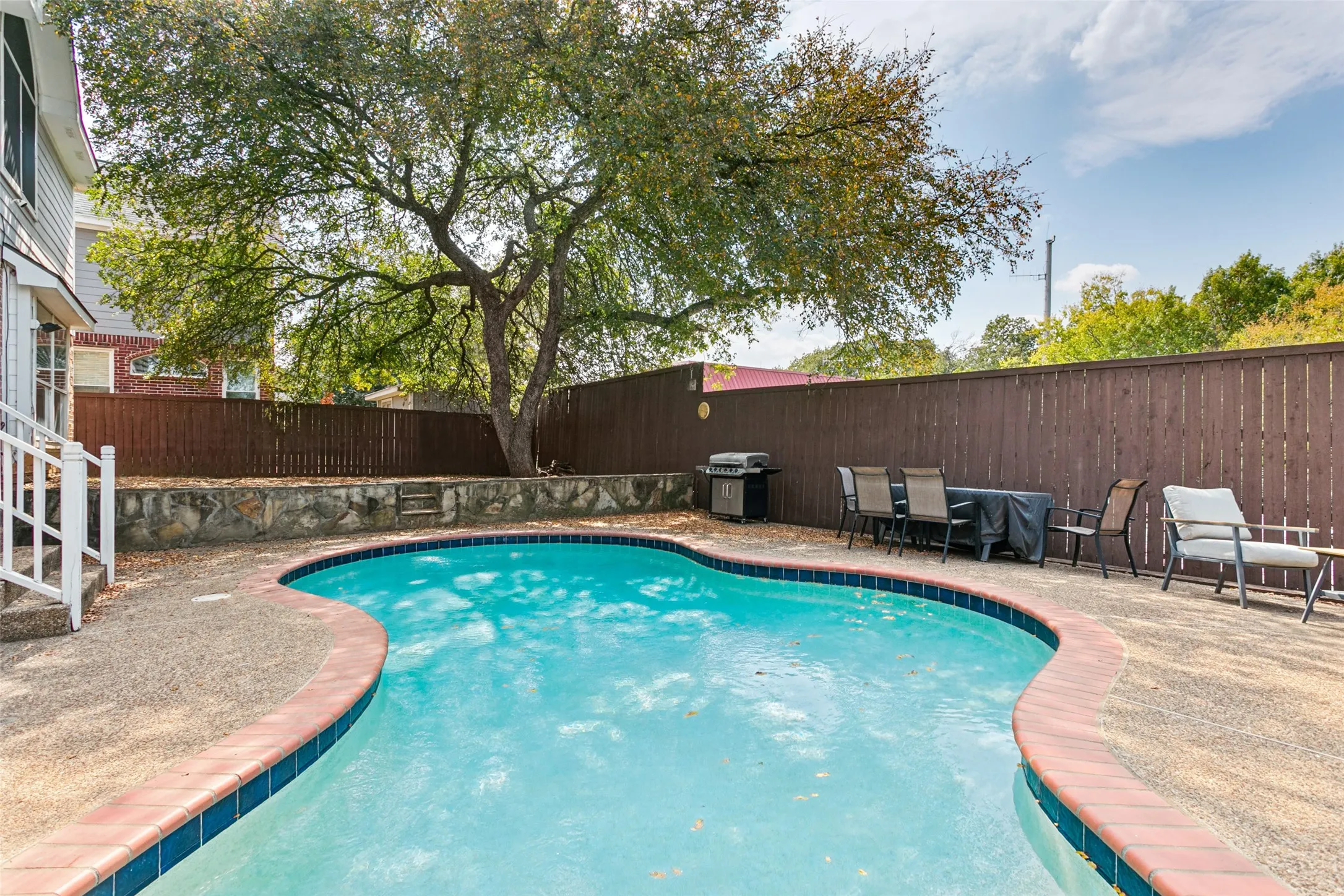Curved swimming pool with an exposed aggregate concrete deck and brick coping