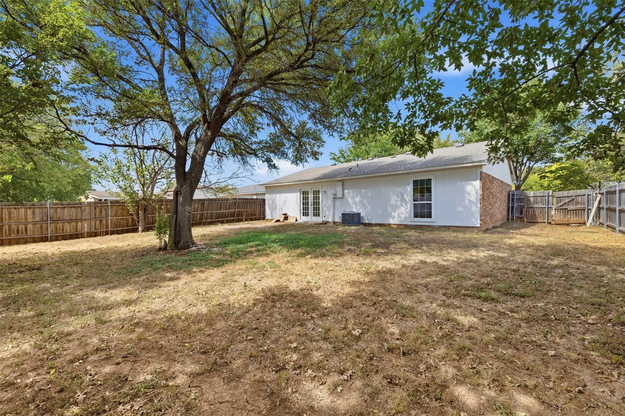 Expansive backyard featuring a mature tree and wood privacy fencing