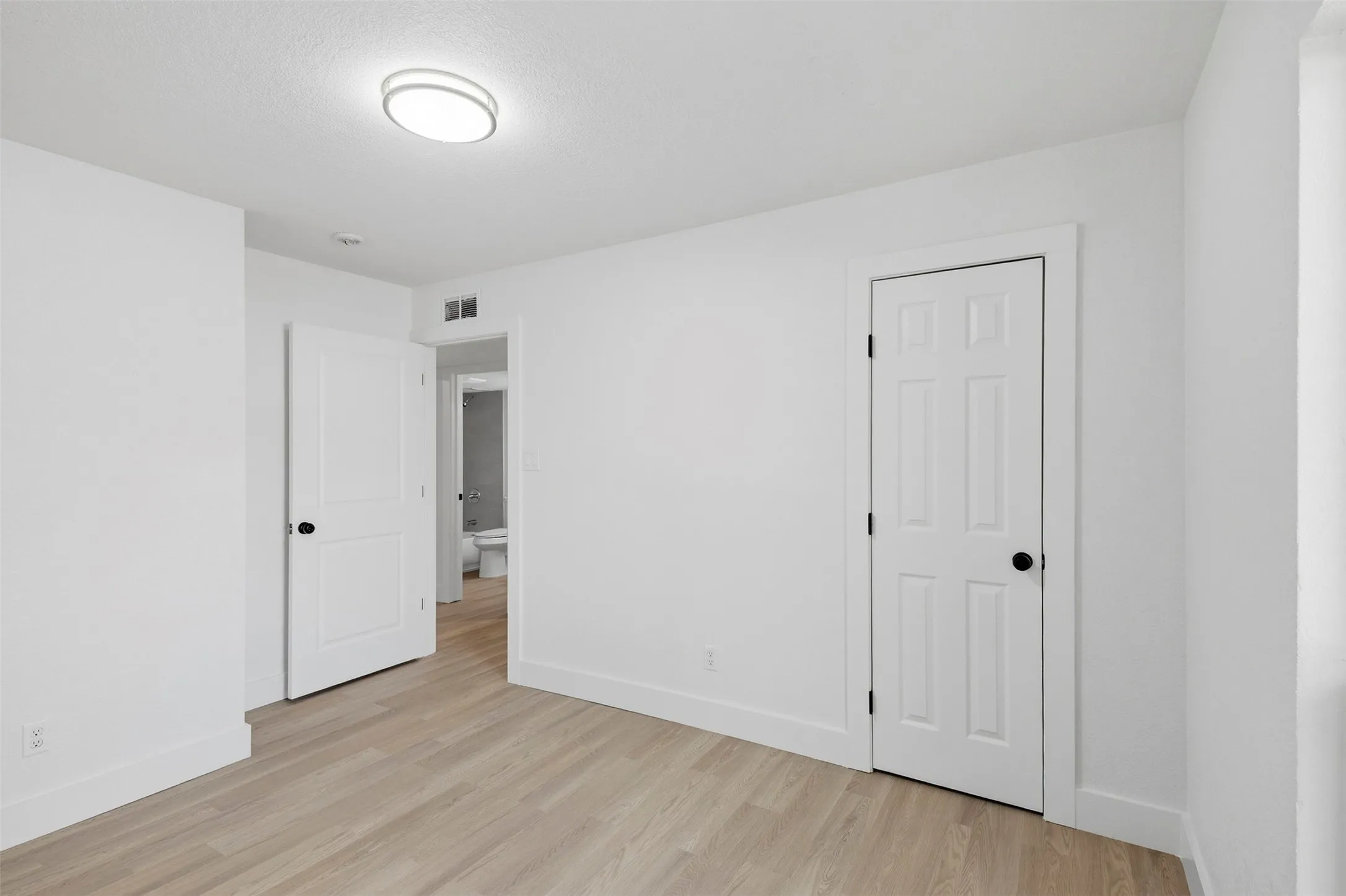 Light wood-finish flooring with white baseboards and trim