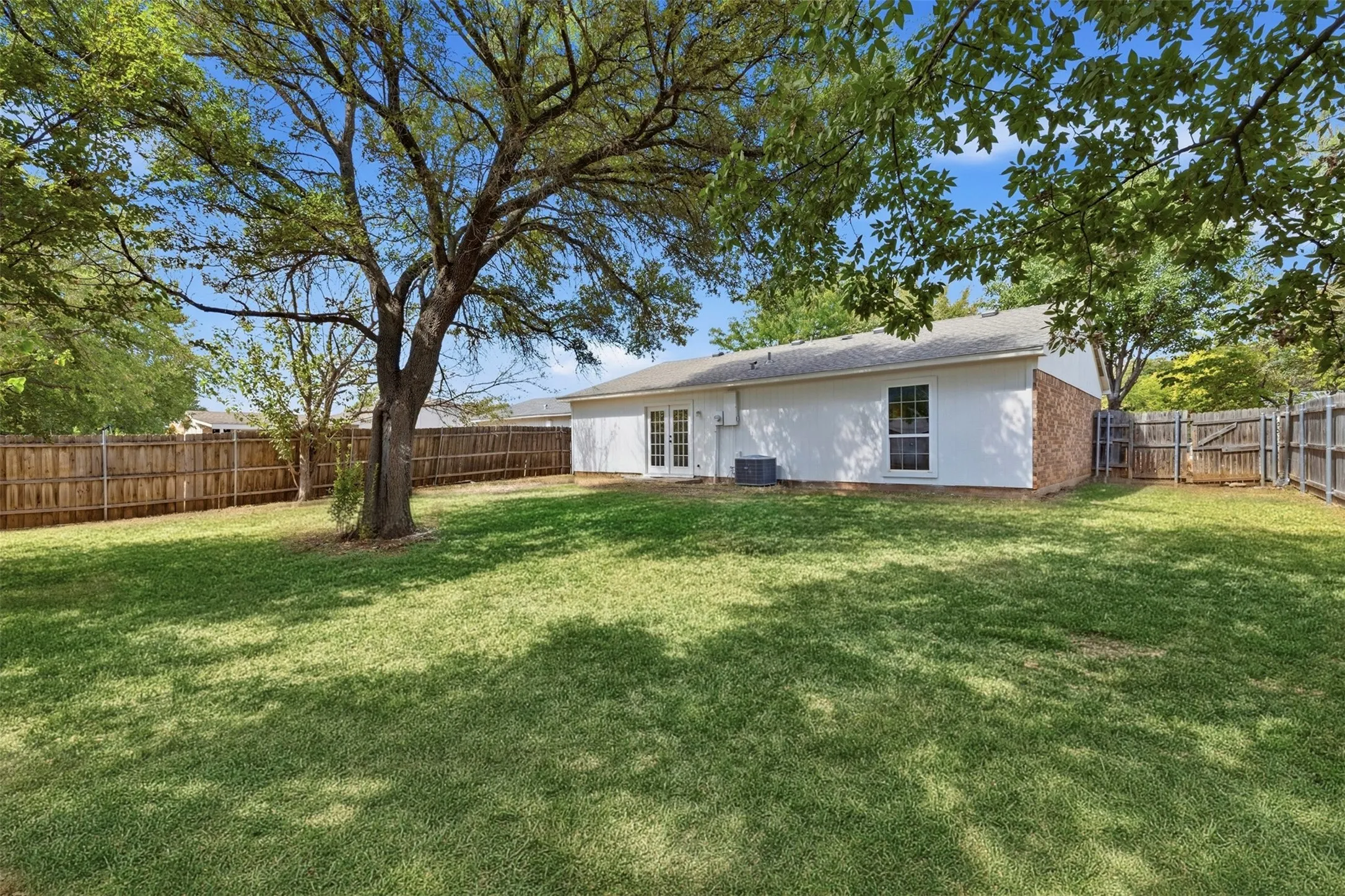 Greened backyard with established shade trees, and a full privacy fence.