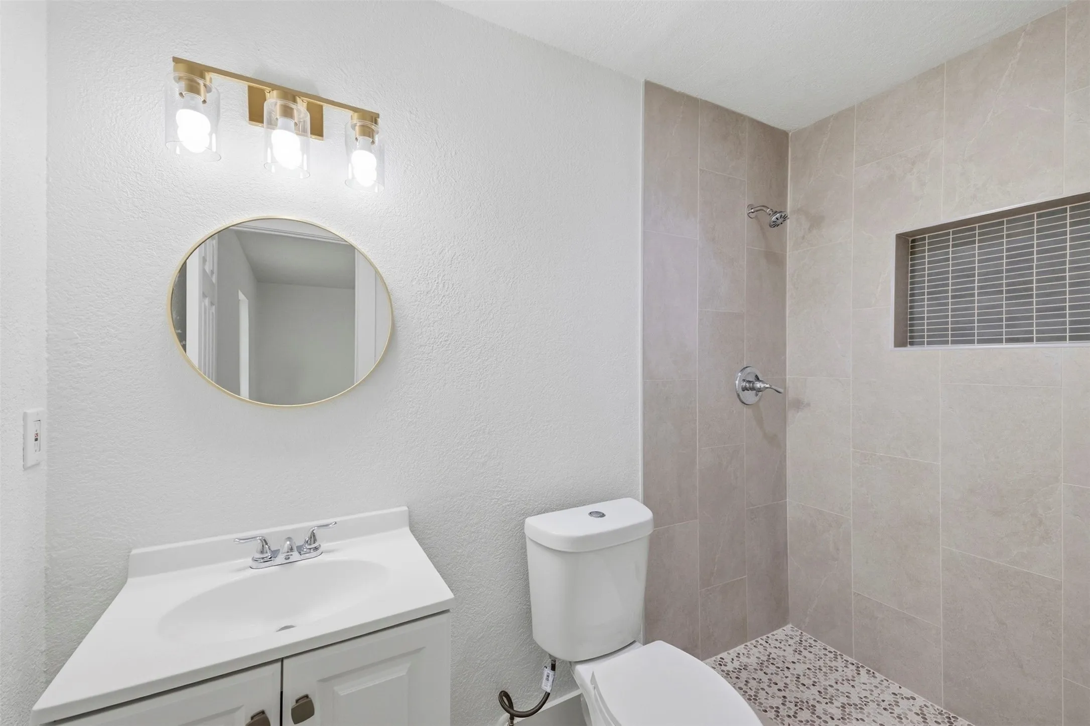 Modern vanity with integrated sink, gold-finish mirror, and coordinating vanity light