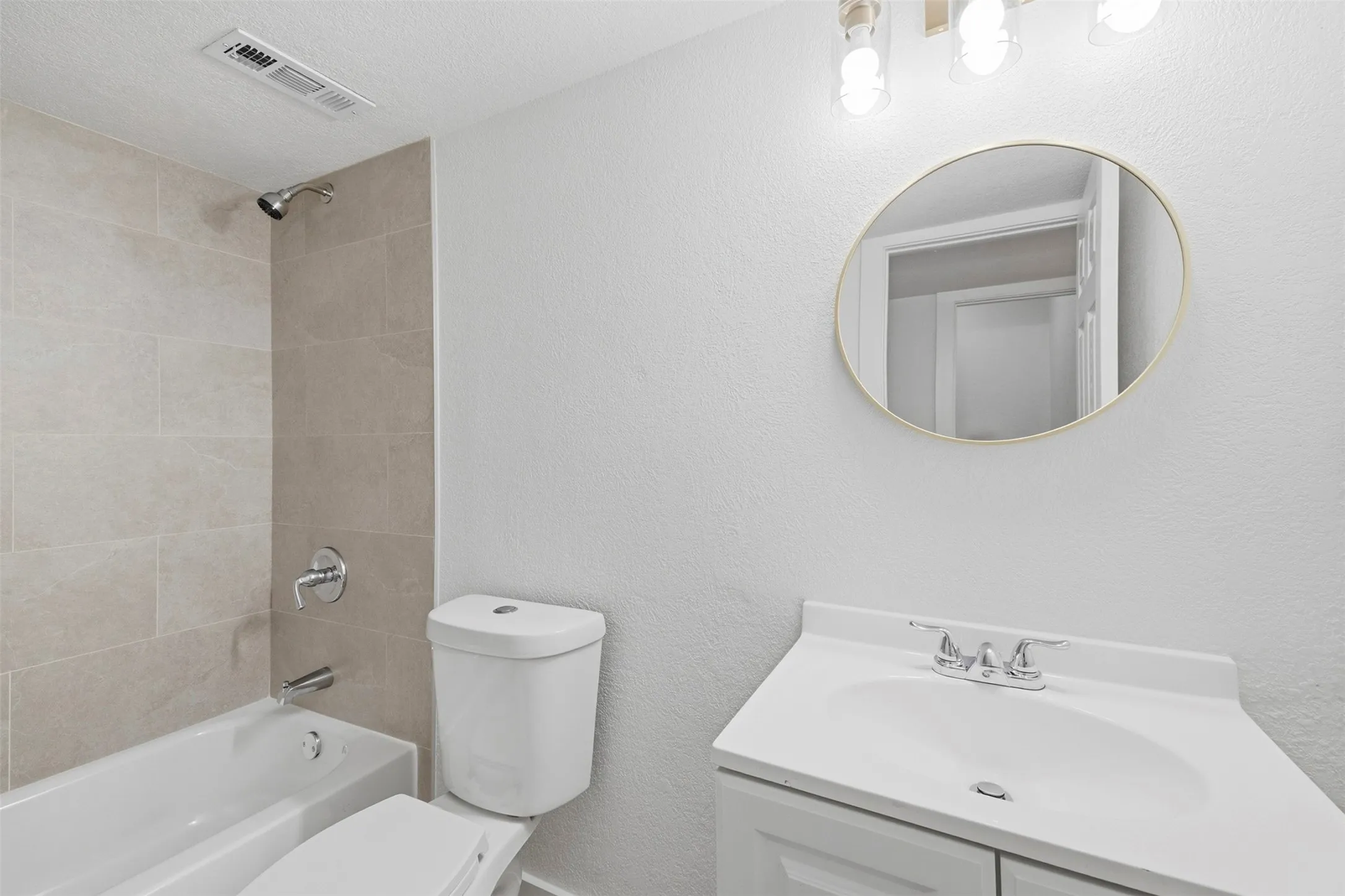White vanity with integrated sink, chrome faucet, and round framed mirror