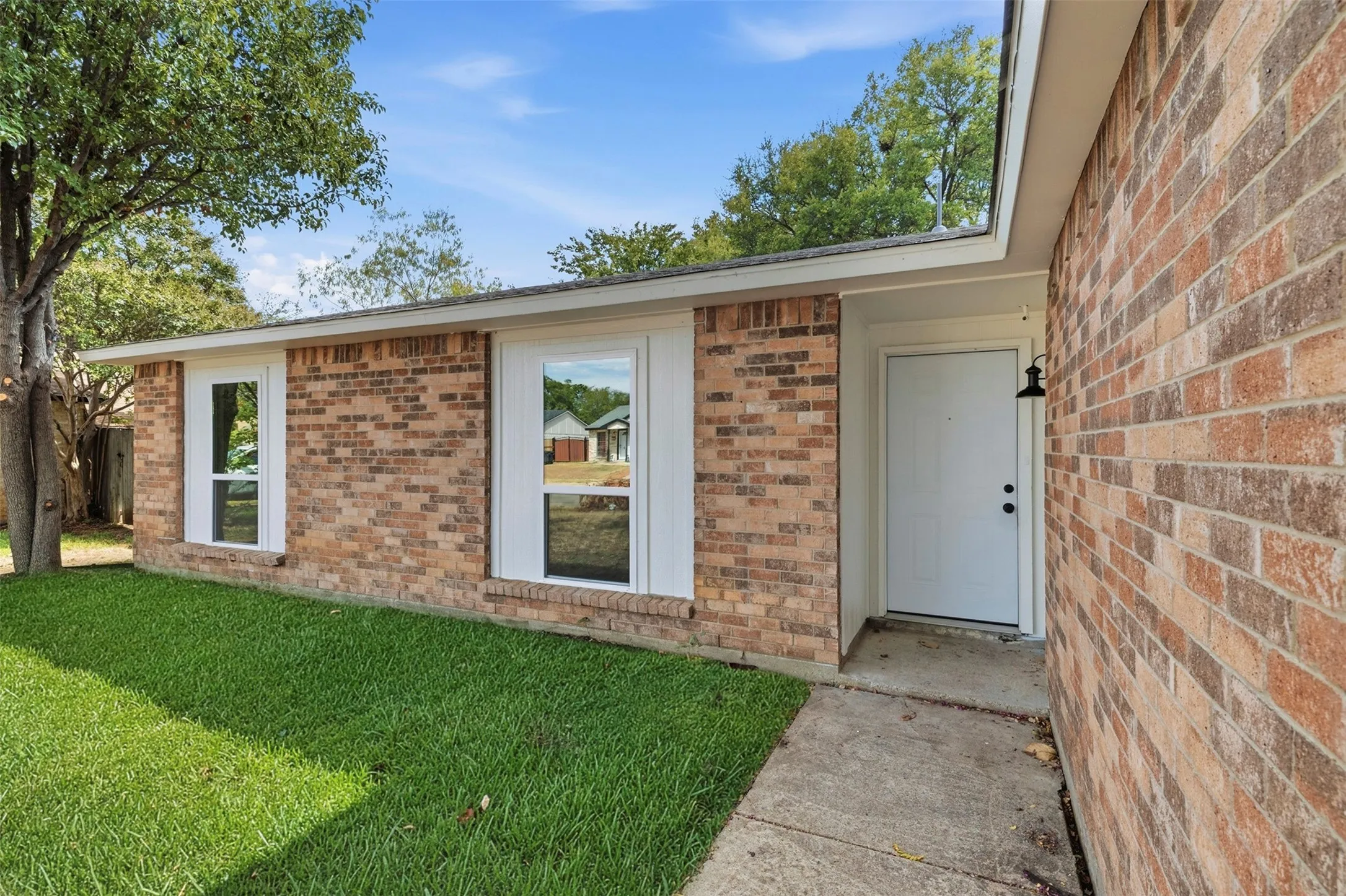 Brick exterior with white trim, a covered entry, and a concrete walkway