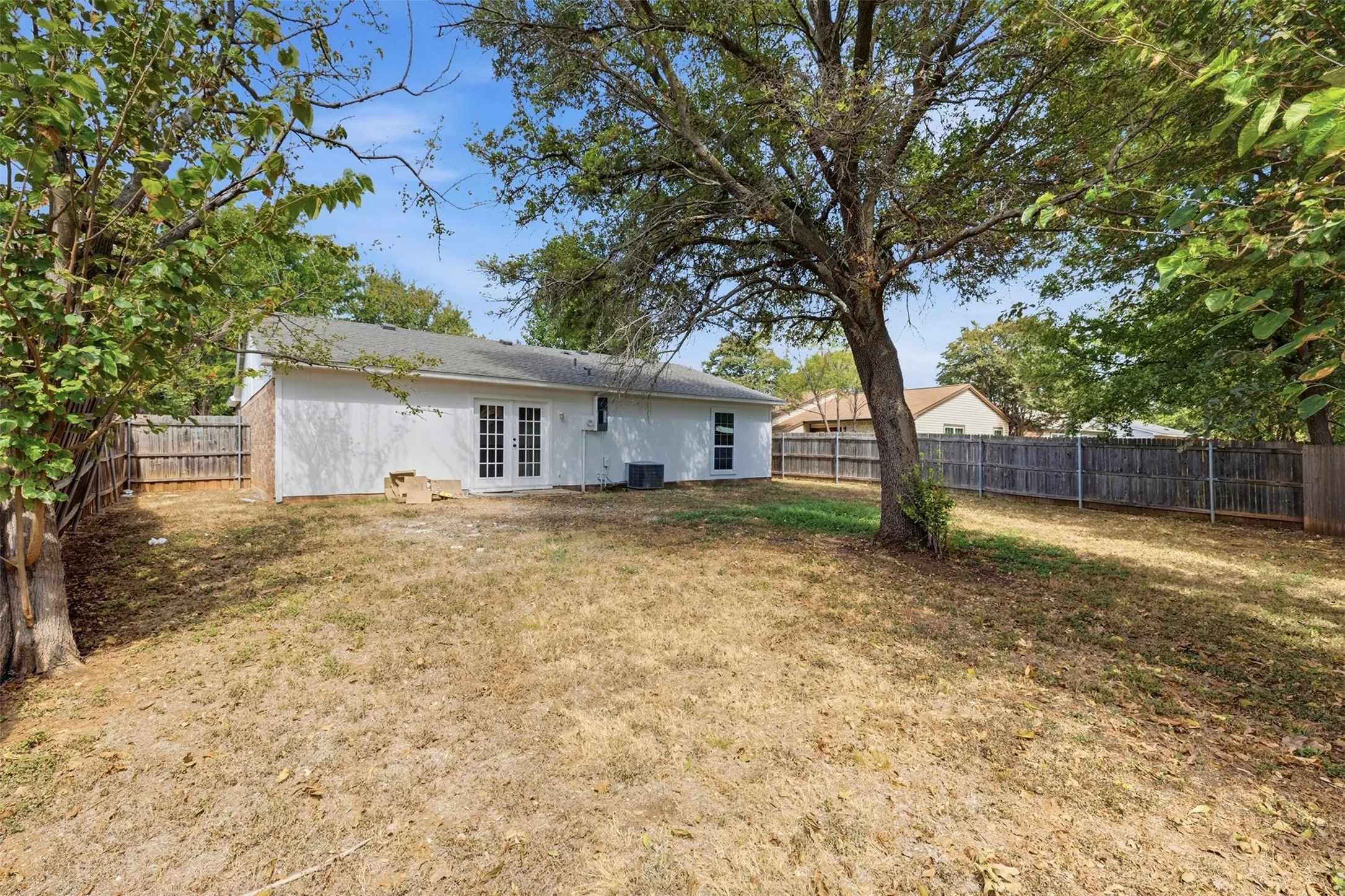 Expansive backyard featuring mature trees and wood fencing